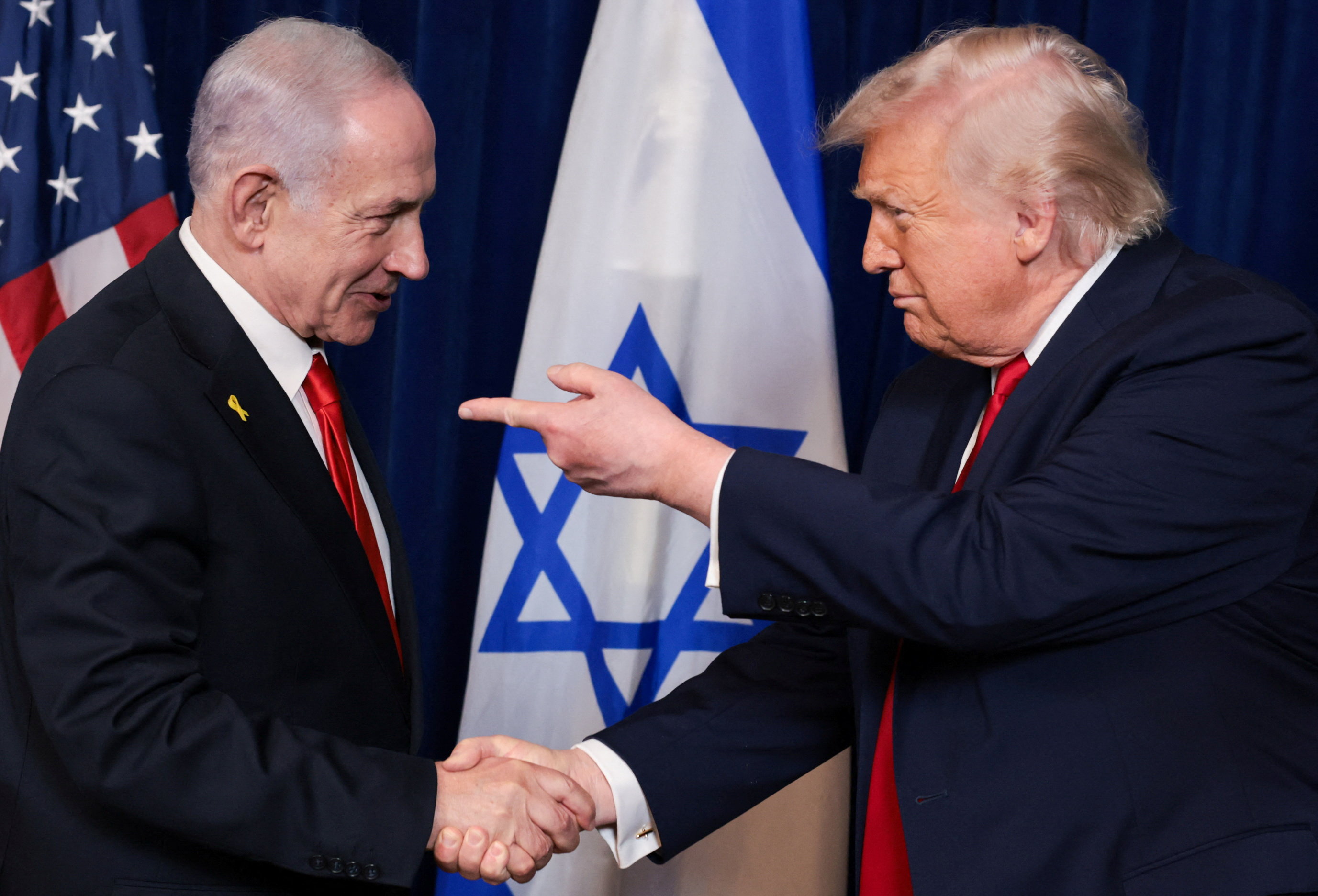 U.S. President Donald Trump points his finger towards Israeli Prime Minister Benjamin Netanyahu as they shake hands during a press conference
