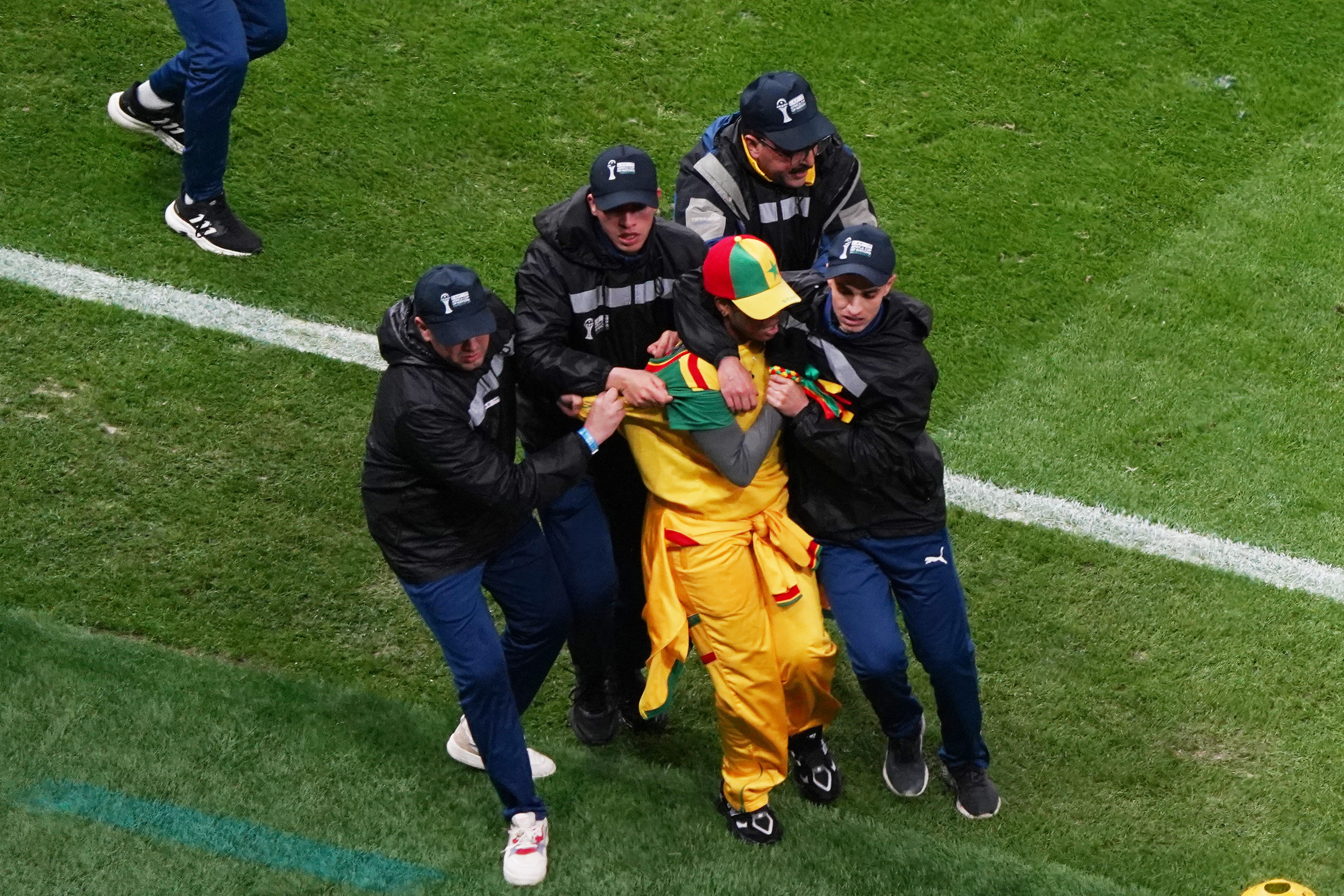 Security staff tackle A Senegal fan who invaded the pitch after Morocco were awarded a penalty following a VAR review