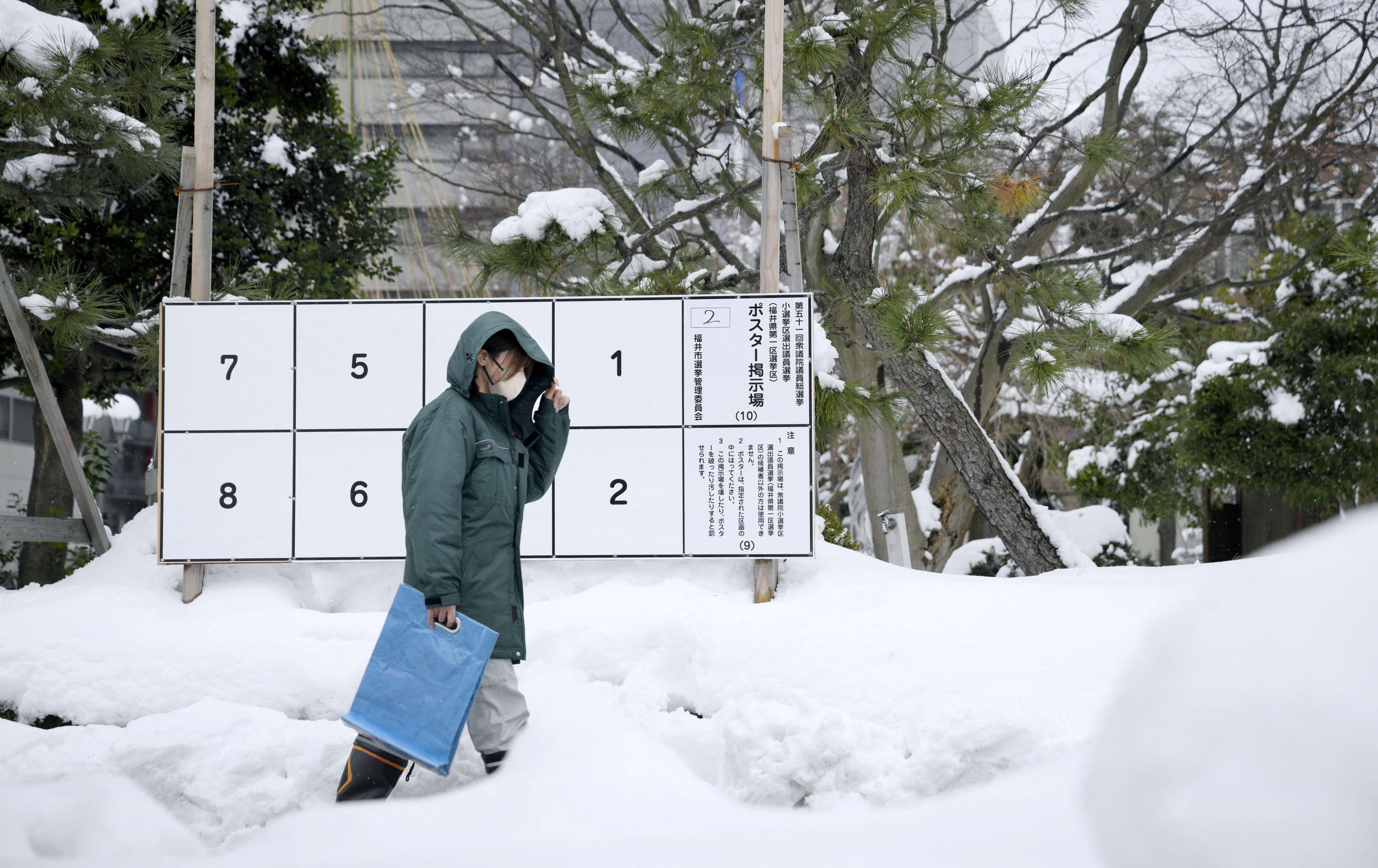 A person walks past a bulletin board for posters of candidates for the February 8 snap election, where snow has accumulated, in Fukui, Japan, January 26, 2026, in this photo taken by Kyodo. Mandatory credit Kyodo/via REUTERS ATTENTION EDITORS - THIS IMAGE WAS PROVIDED BY A THIRD PARTY. EDITORIAL USE ONLY. MANDATORY CREDIT. JAPAN OUT. NO COMMERCIAL OR EDITORIAL SALES IN JAPAN.