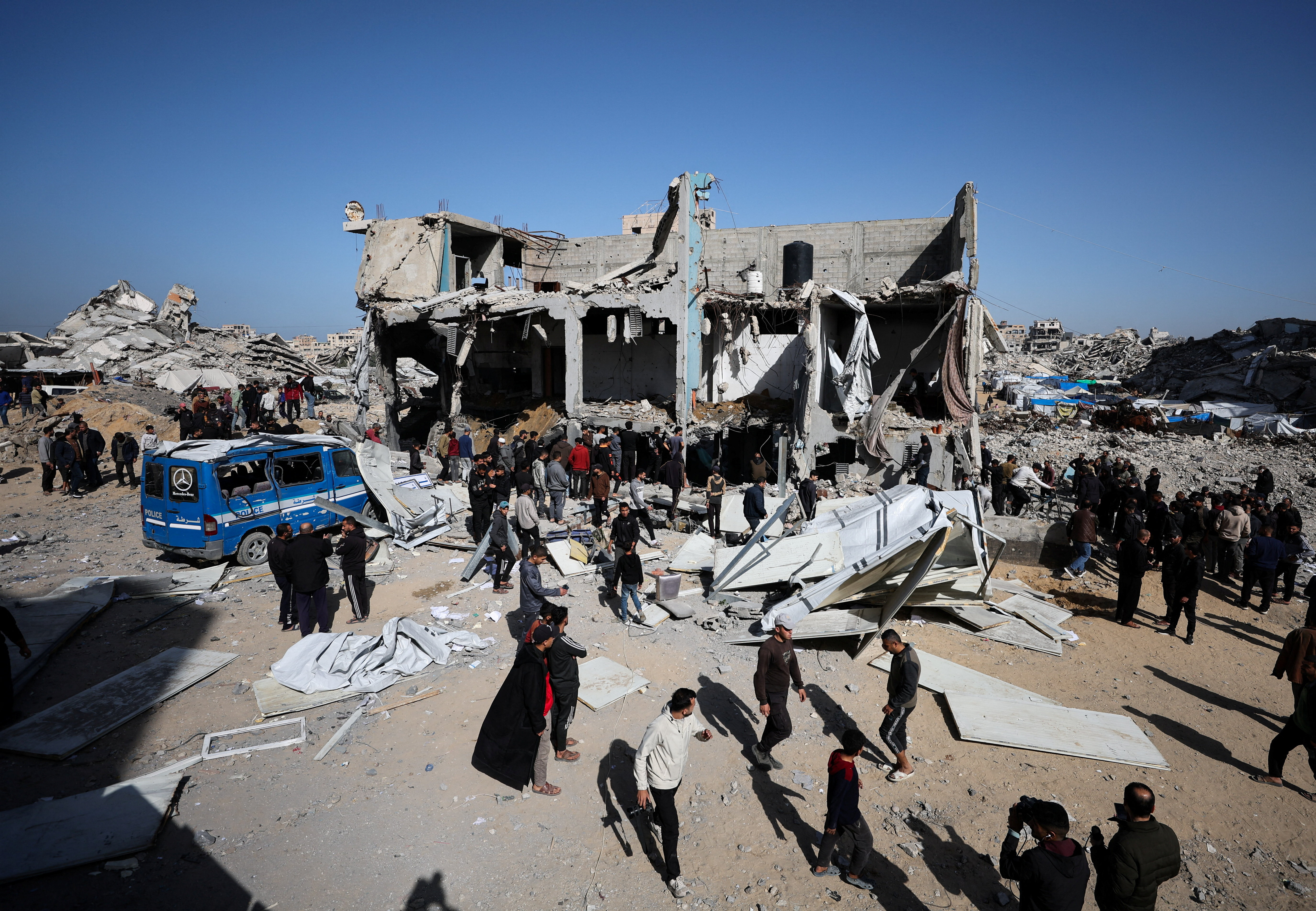 Palestinians stand outside destroyed building