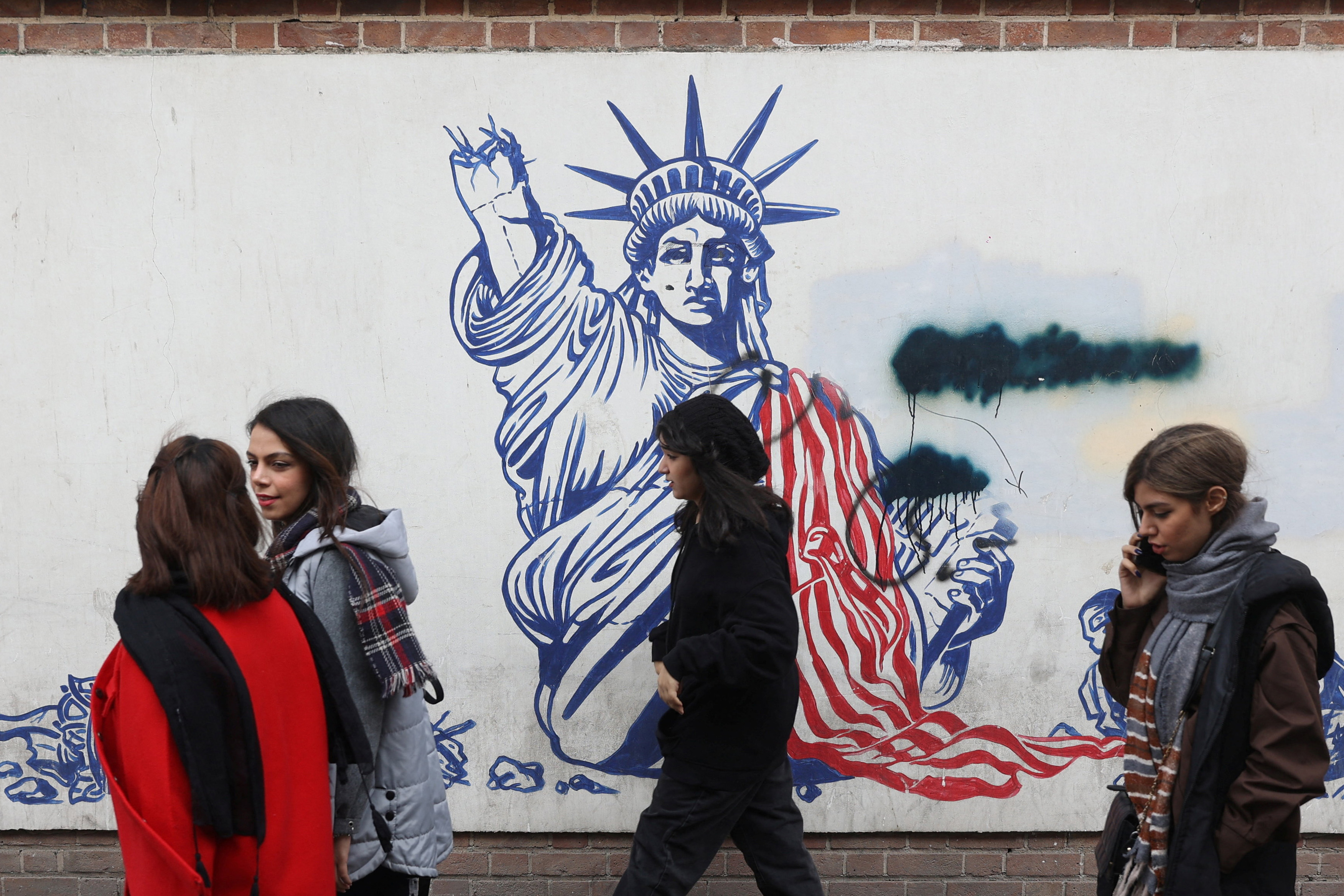 Women walk past an anti-US mural on a street in Tehran, Iran, on February 5, 2026. [Majid Asgaripour/West Asia News Agency via Reuters]
