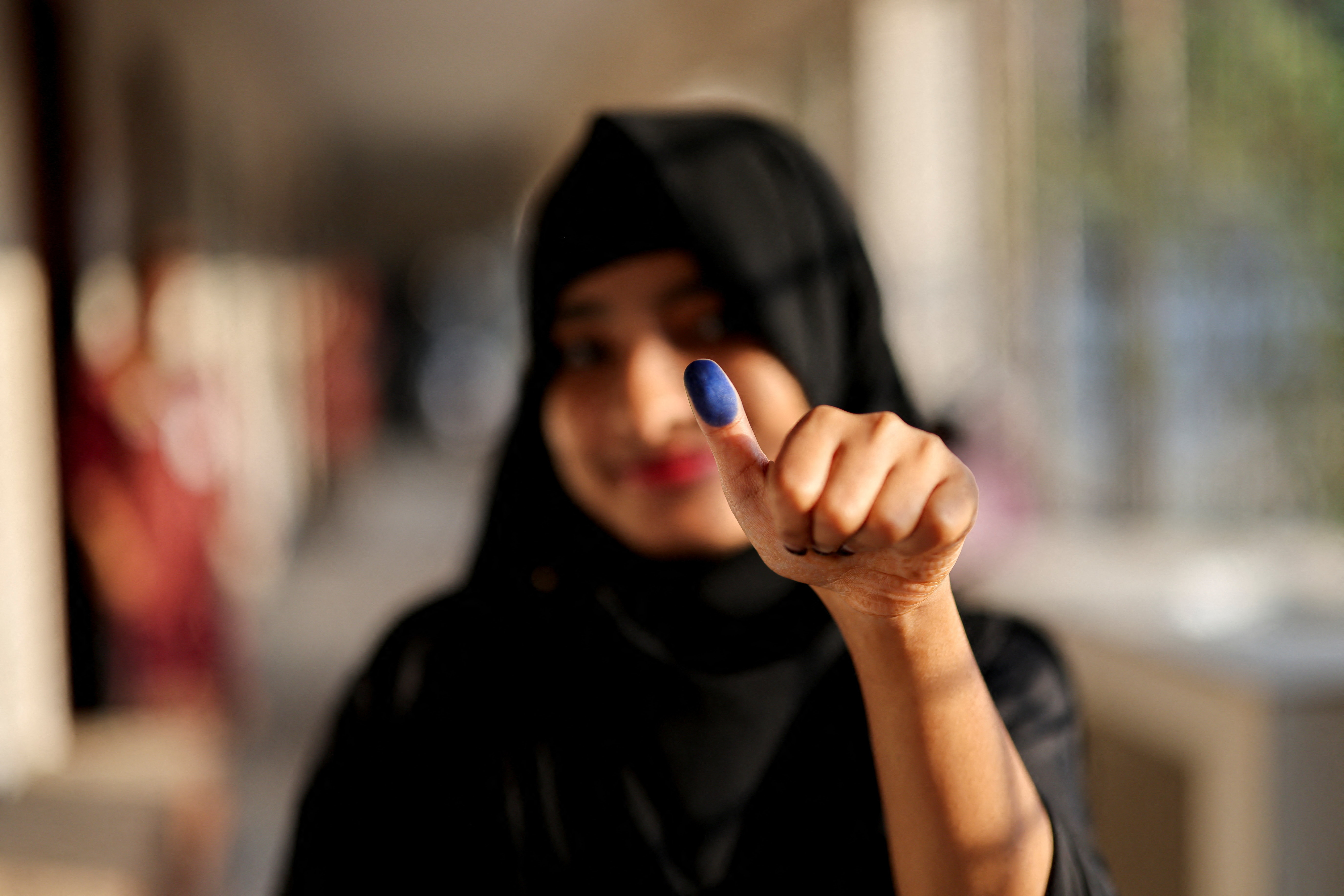 A woman shows her thumb with an ink mark after casting her vote during the 13th general election in Dhaka, Bangladesh