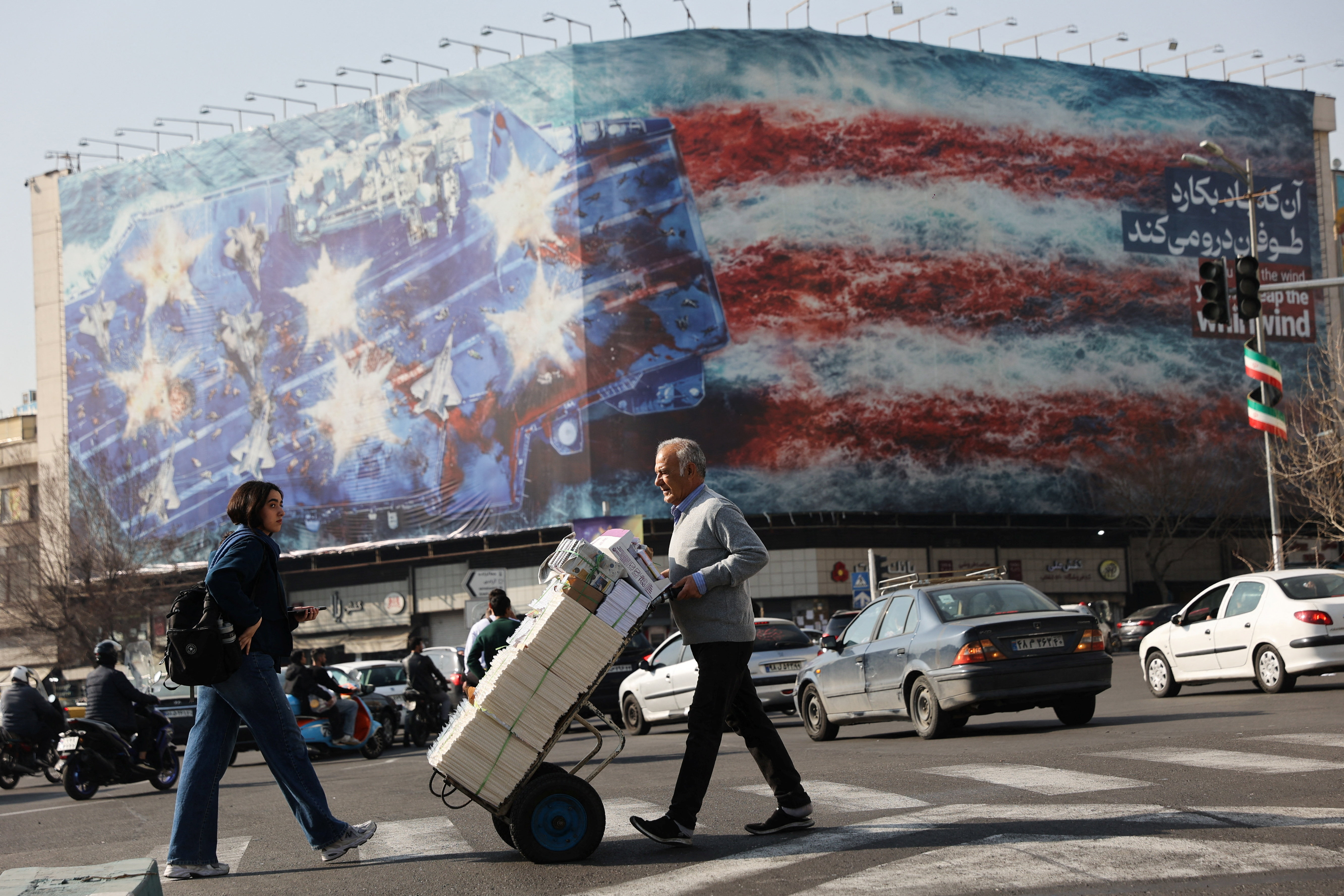 People walk past an anti-U.S. billboard in Tehran, Iran, February 19, 2026.