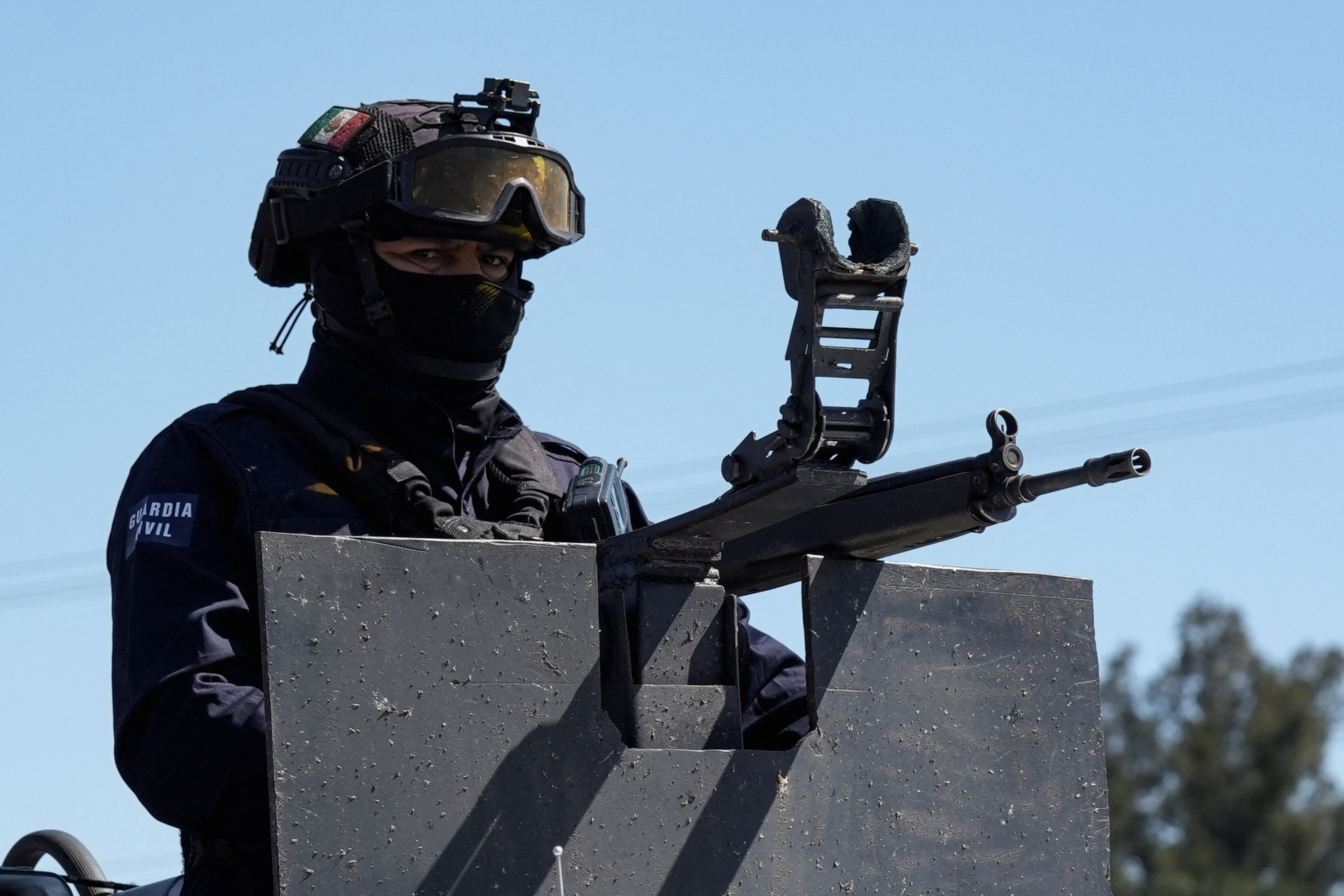 A police officer mans a gun atop a vehicle as workers (not pictured) remove the wreckage of a trailer used to block a highway after a series of blockades and attacks by organized crime following a military operation in which cartel boss Nemesio Oseguera, "El Mencho," was killed, in Ecuandureo, Mexico, February 23, 2026. [Ivan Arias/Reuters]