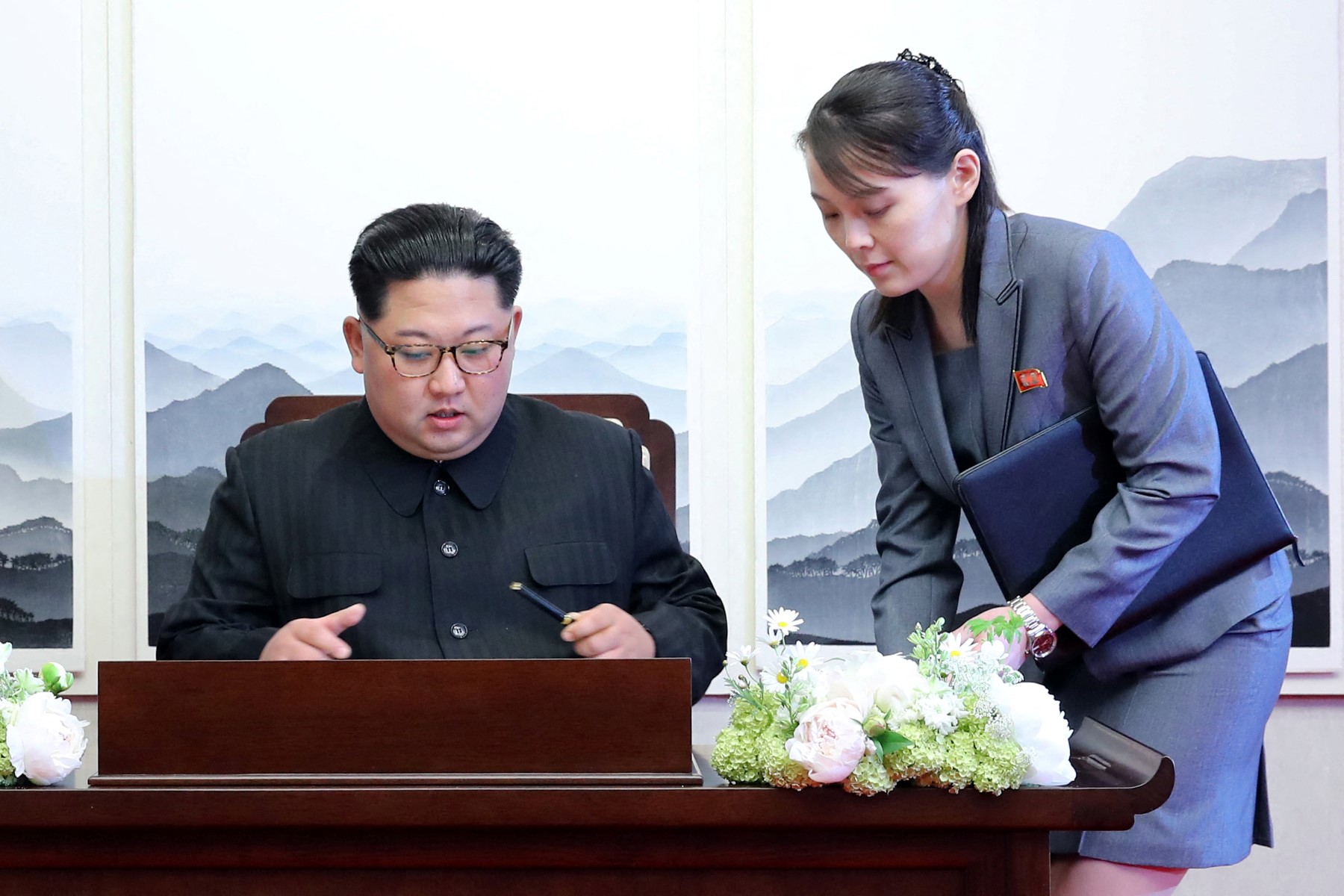 North Korea's leader Kim Jong Un (L) signs the guest book next to his sister Kim Yo Jong (R) during the Inter-Korean summit with South Korea's President Moon Jae-in at the Peace House building on the southern side of the truce village of Panmunjom on April 27, 2018. North Korean leader Kim Jong Un and the South's President Moon Jae-in sat down to a historic summit on April 27 after shaking hands over the Military Demarcation Line that divides their countries in a gesture laden with symbolism. (Photo by Korea Summit Press Pool / Korea Summit Press Pool / AFP)