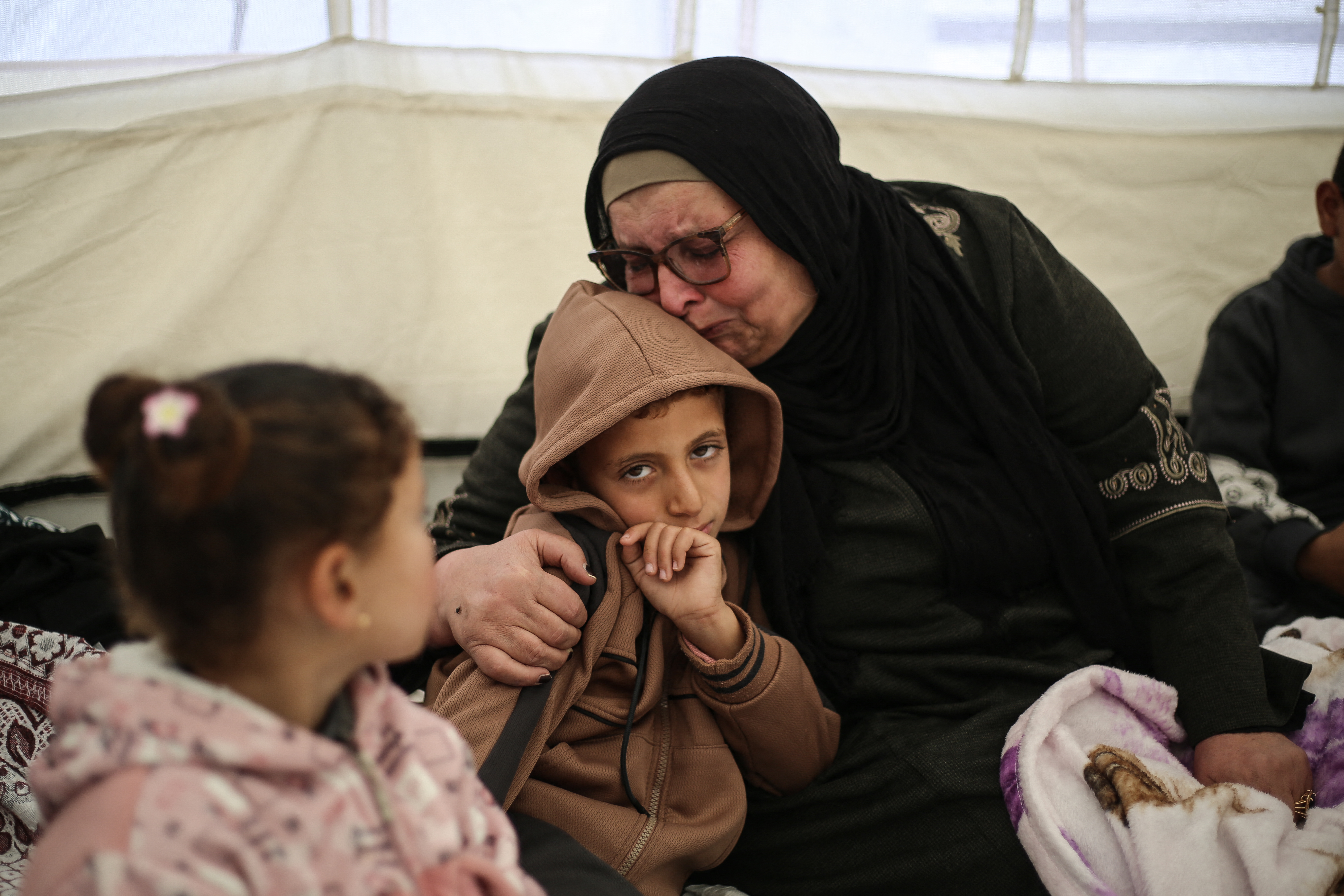 Palestinian Huda Abu Abed reacts while sitting with her loved ones inside her family's tent in Khan Yunis,