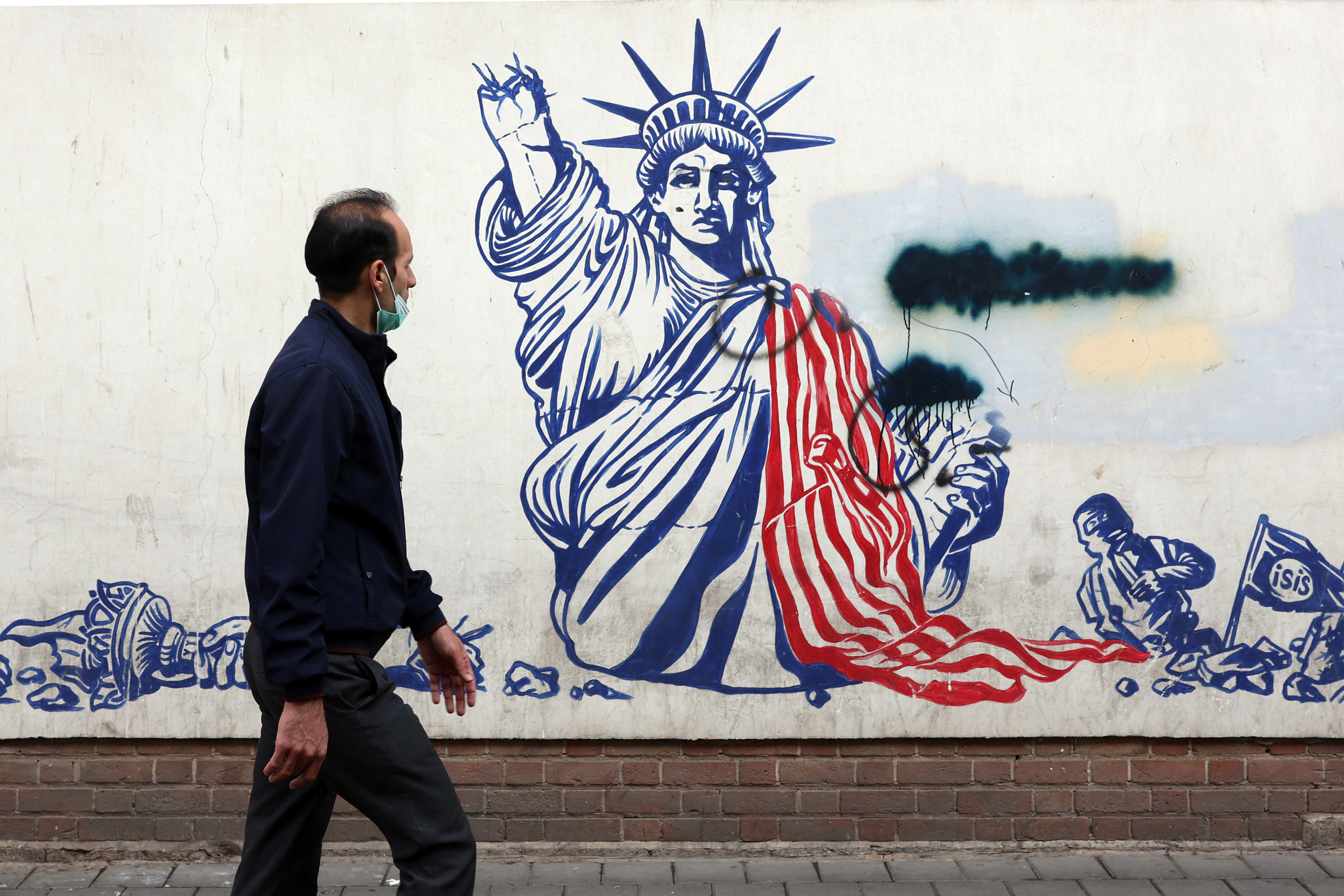 A man walks past a mural depicting the US Statue of Liberty with the torch-bearing arm broken, painted on the outer walls of the former US embassy, in Tehran on February 6, 2026. Iran and the United States began talks in Oman on February 6, with Washington refusing to rule out military action against the Islamic republic over its deadly crackdown on mass protests. (Photo by AFP)