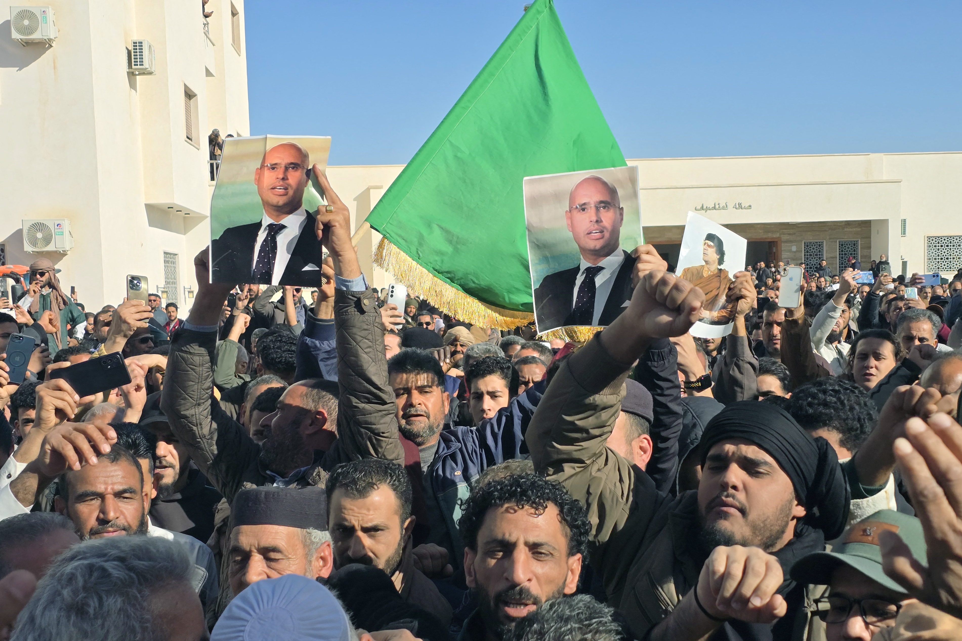Libyans hold up images of the late Saif al-Islam Gaddafi, the son of Libya's late longtime ruler, prior to his funeral in Bani Walid