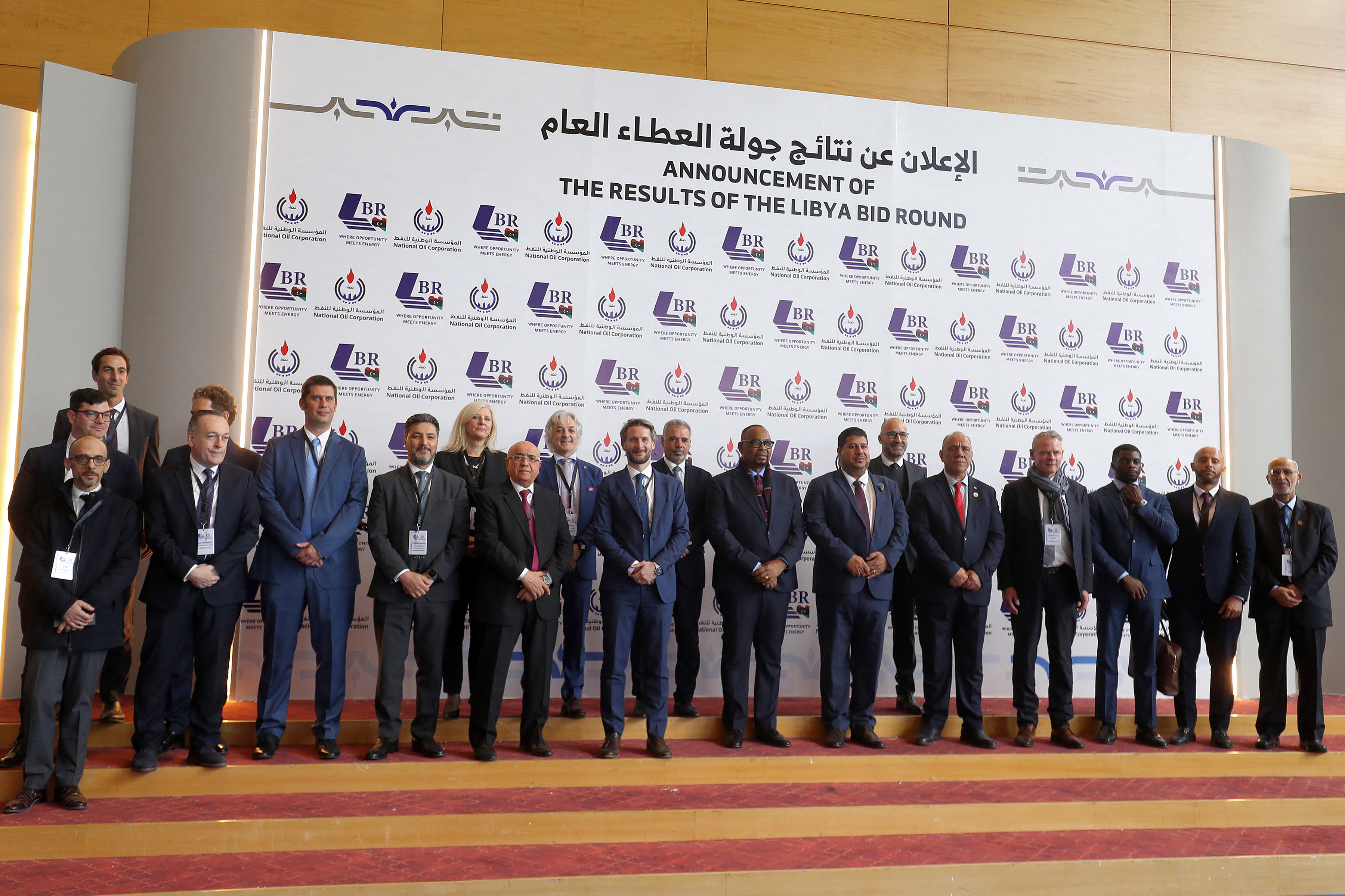 Masoud Suleiman Musa, acting chairman of Libya's National Oil Corporation (NOC), and other corporate represntatives pose for a family photo during a conference announcing the first new grants of oil exploration and production licences in 17 years, in Libya's capital Tripoli on February 11, 2026. The hydrocarbon-rich country is seeking to draw major global energy companies back, while boosting daily oil production by 850,000 barrels over the next 25 years. The winners of the latest bidding round included US oil giant Chevron and Nigeria's Aiteo. (Photo by Mahmud Turkia / AFP)