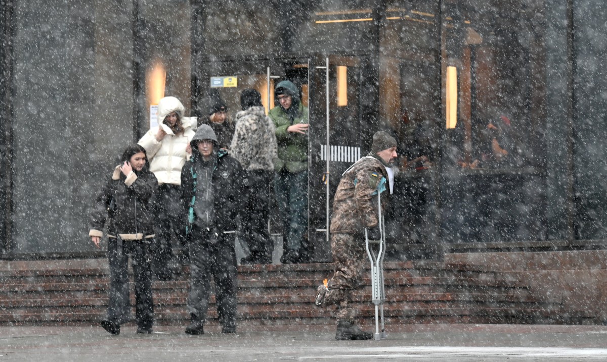 A wounded Ukrainian serviceman walks in a street in Kyiv during snow fall on February 15, 2026, amid Russian invasion in Ukraine. (Photo by Sergei SUPINSKY / AFP)