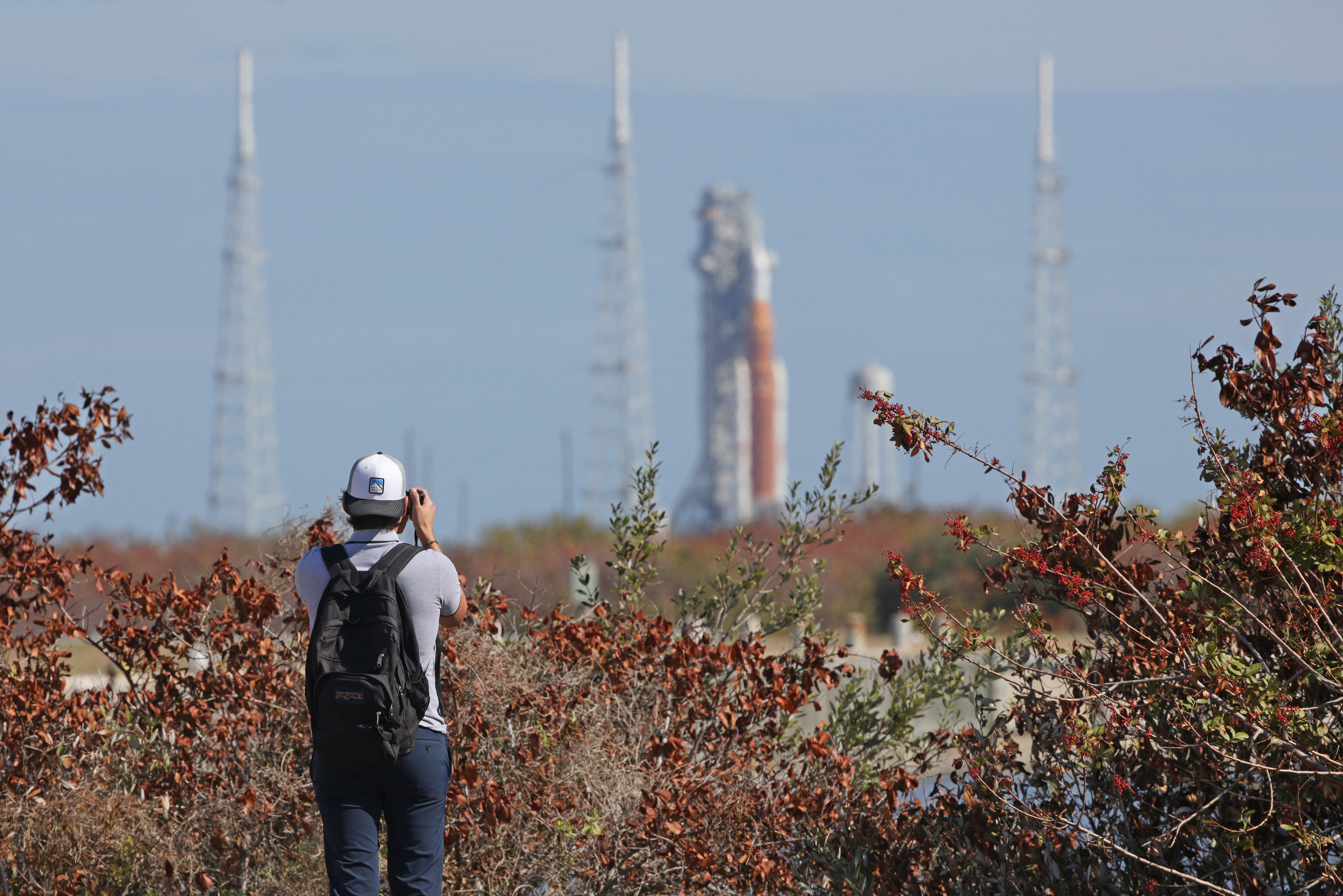A journalist snaps a photo of NASA's Artemis II Space Launch System (SLS) rocket and Orion spacecraft seen in the distance from the Kennedy Space Center in Cape Canaveral, Florida on February 20, 2026.