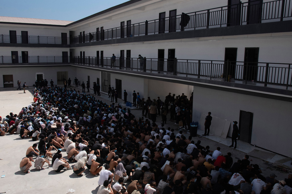 People from China, Vietnam and Ethiopia, believed to have been trafficked and forced to work in scam centers, sit with their faces masked while in detention after being released from the centers in Myawaddy, Myanmar