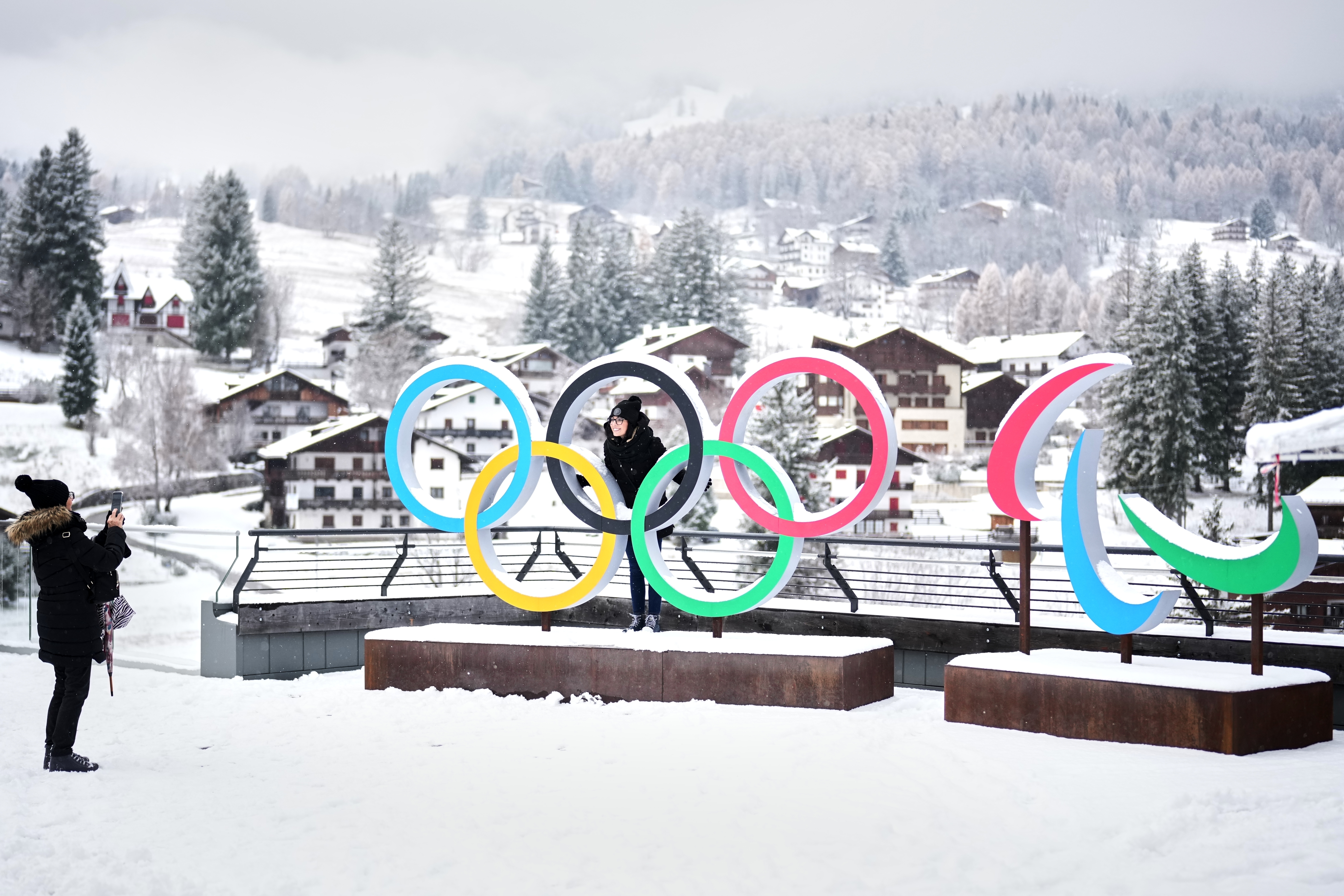 People take photos in front of the Milan Cortina Winter Olympics and Paralympics rings, in Cortina D'Ampezzo