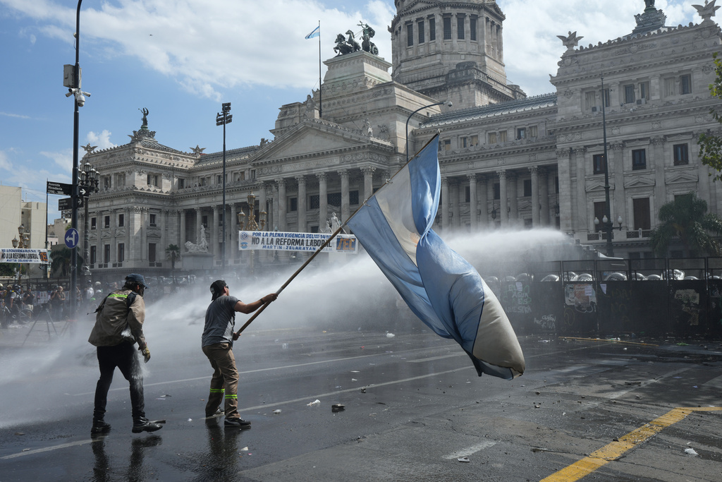 A protester with an Argentine flag being sprayed with a water cannon