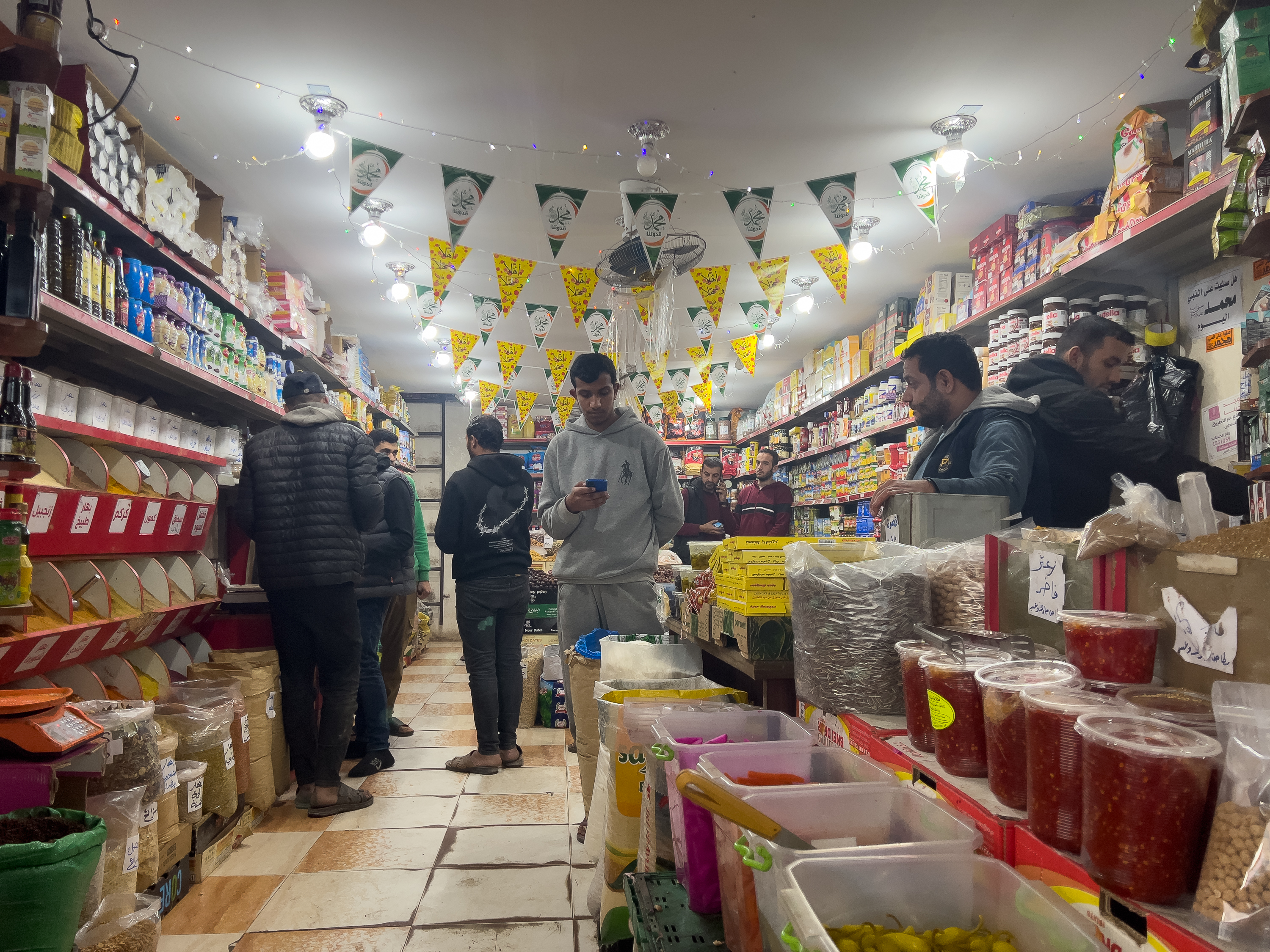 People purchasing goods at a grocery shop at Al-Zawya market [Ola al-Asi/ Al Jazeera]