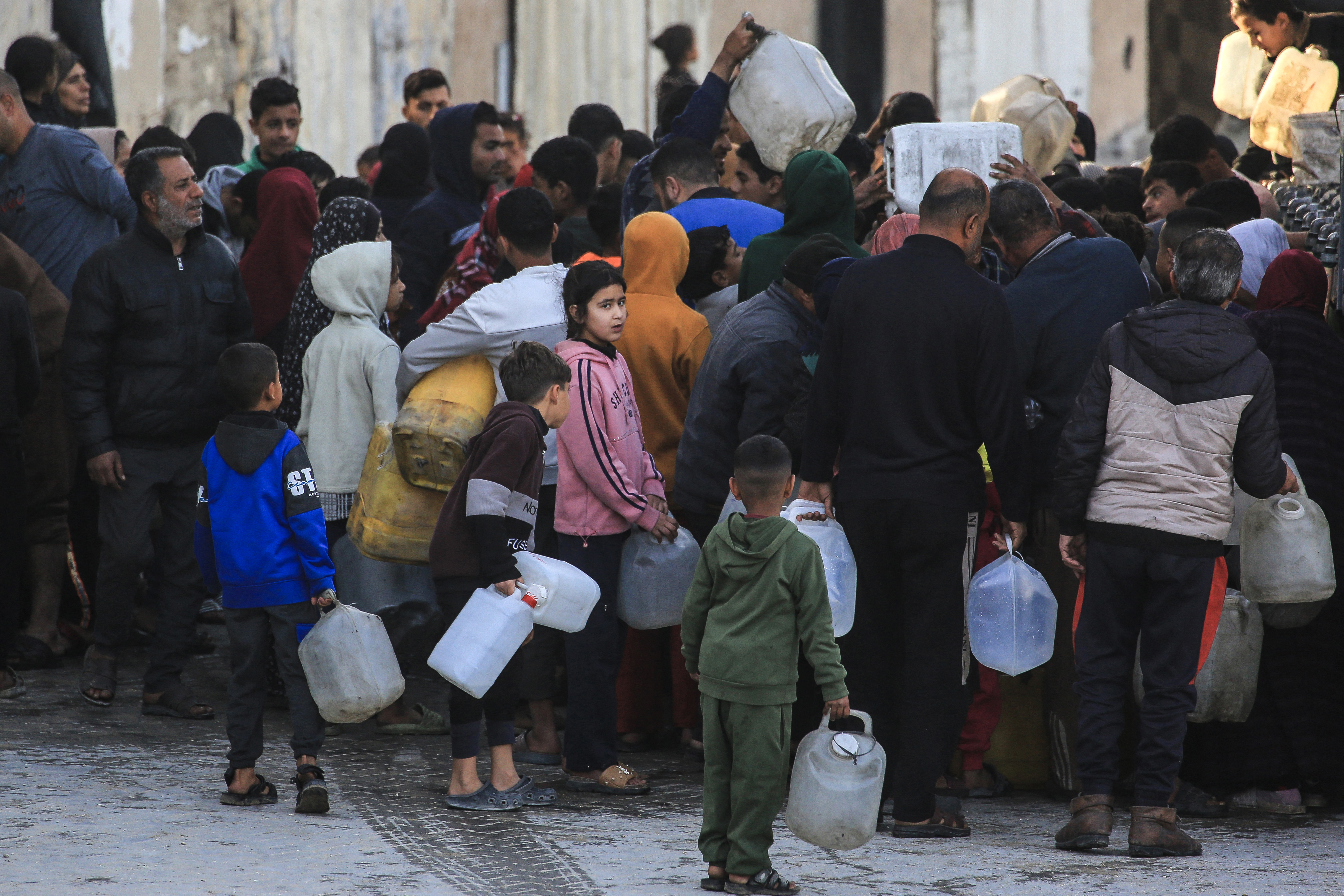 Displaced Palestinians wait to fill jerrycans with water collected from a desalination plant in Khan Yunis, southern Gaza Strip, on February 7, 2026.