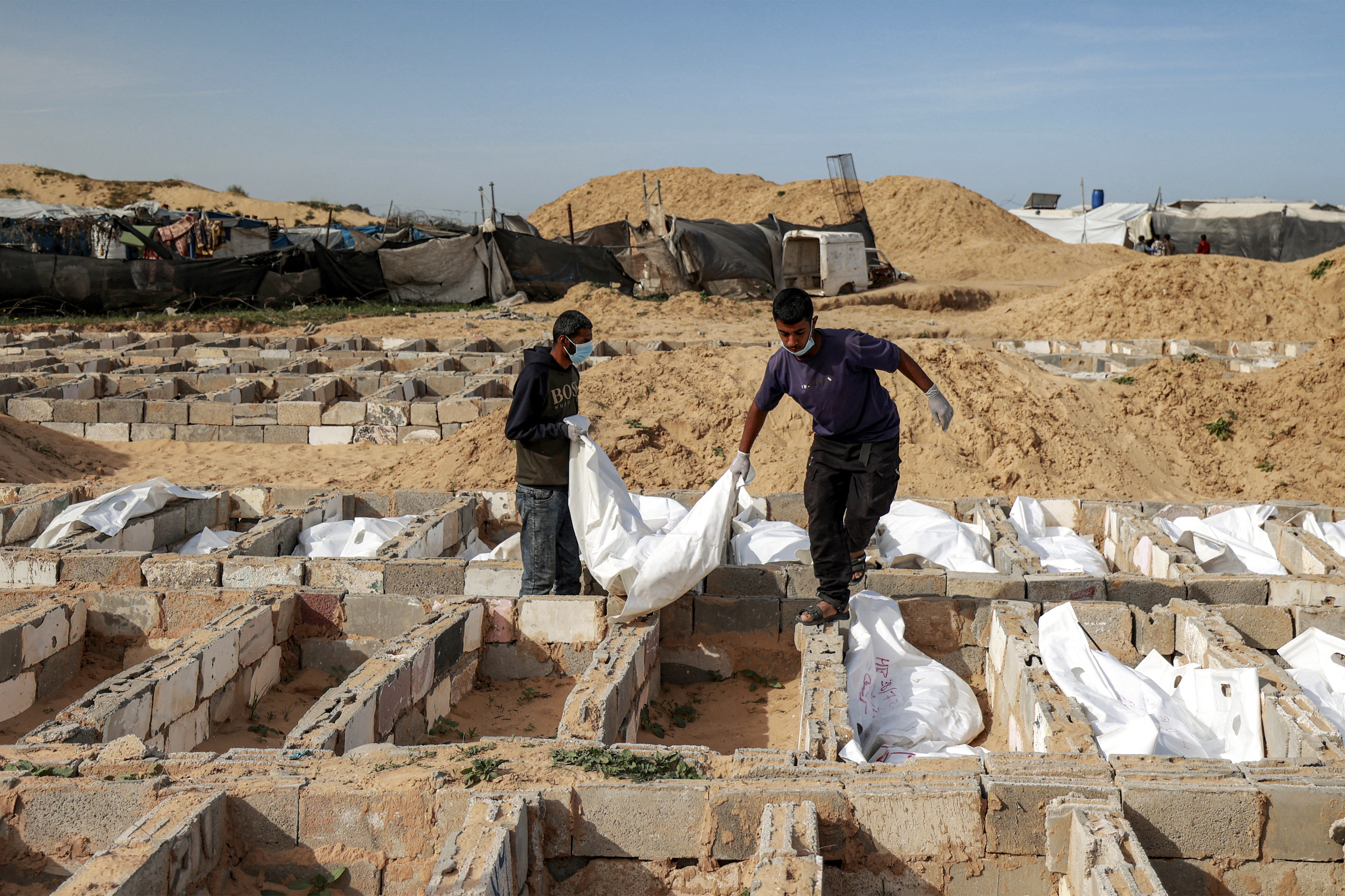 EDITORS NOTE: Graphic content / Men carry a body bag as they bury one of 53 unidentified bodies at a cemetery in Deir el-Balah in the central Gaza Strip on February 13, 2026.