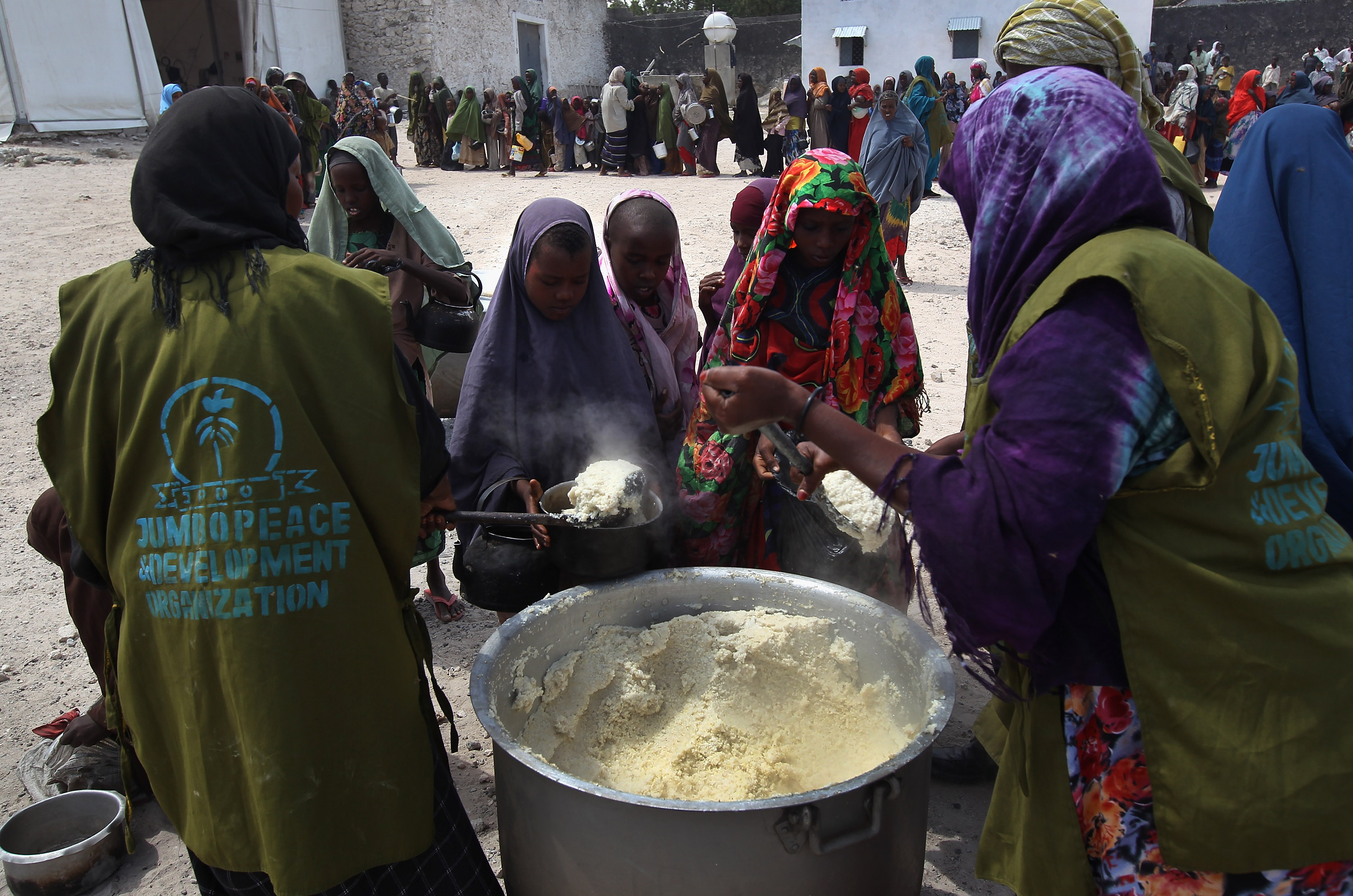 MOGADISHU, SOMALIA - AUGUST 14: Women and children receive food aid on August 14, 2011 in Mogadishu, Somalia. A local Somali agency distributes cooked porridge from World Food Progam to hundreds of women and children at a distrubution center near the Mogadishu airport. The WFP, however, has had difficulty distributing aid to camps for those affected by famine and drought located farther from secure areas near the airport. More than 100,000 people have flooded into Mogadishu, fleeing drought conditions in southern Somalia. (Photo by John Moore/Getty Images)