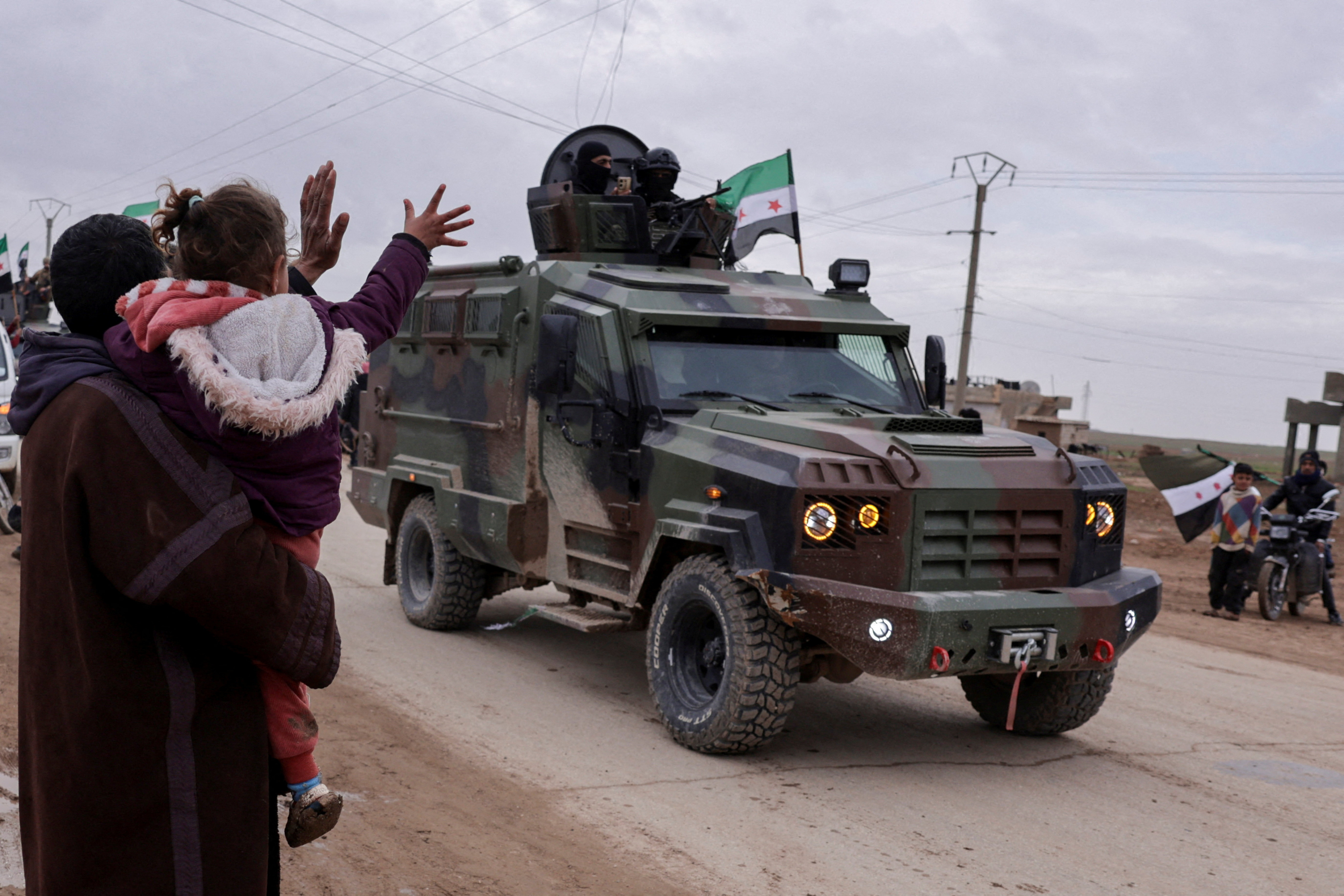 People wave, as internal security forces affiliated with the Syrian government prepare to enter the city of Qamishli in northeastern Syria, following an agreement between Damascus and the Syrian Democratic Forces, in Tel Brak, near al-Hasakah, Syria, February 3, 2026. REUTERS/Khalil Ashawi TPX IMAGES OF THE DAY