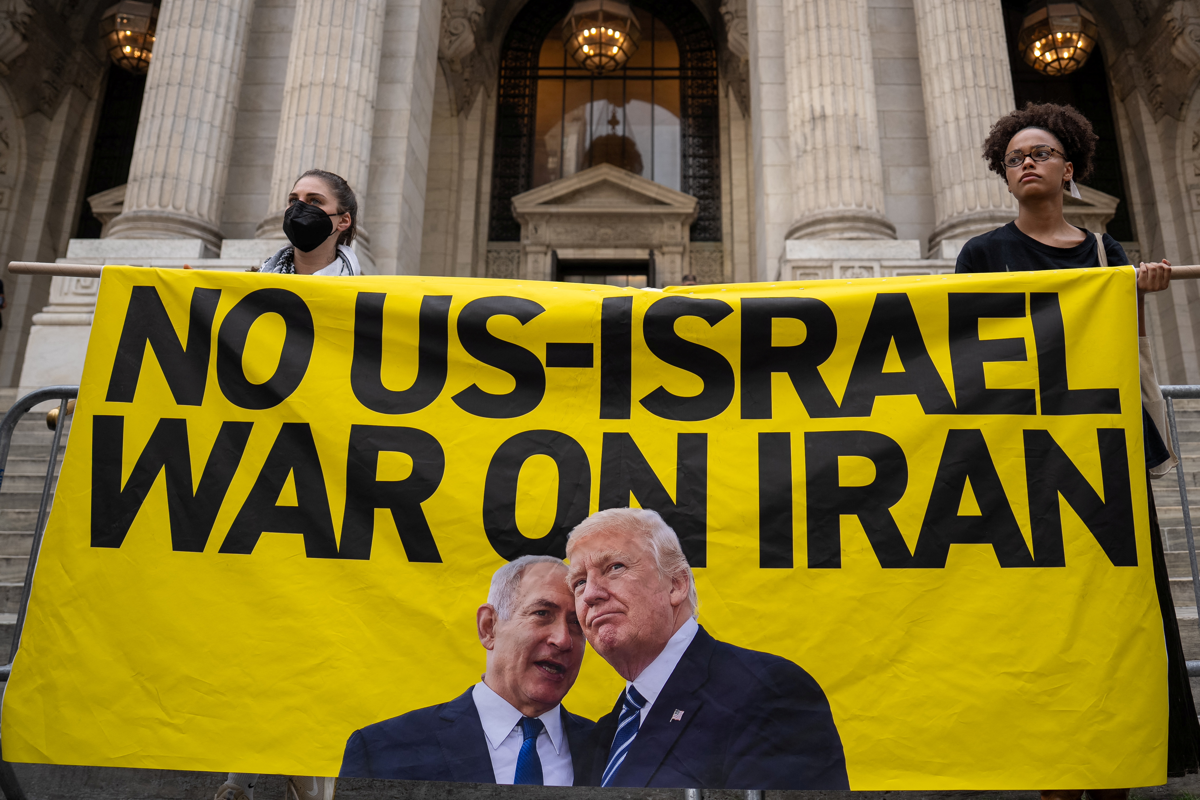 Protesters hold a banner with a message and images of US President Donald Trump and Israeli Prime Minister Benjamin Netanyahu during a 'No War on Iran' rally in New York City, US, June 18, 2025. [David 'Dee' Delgado/Reuters]