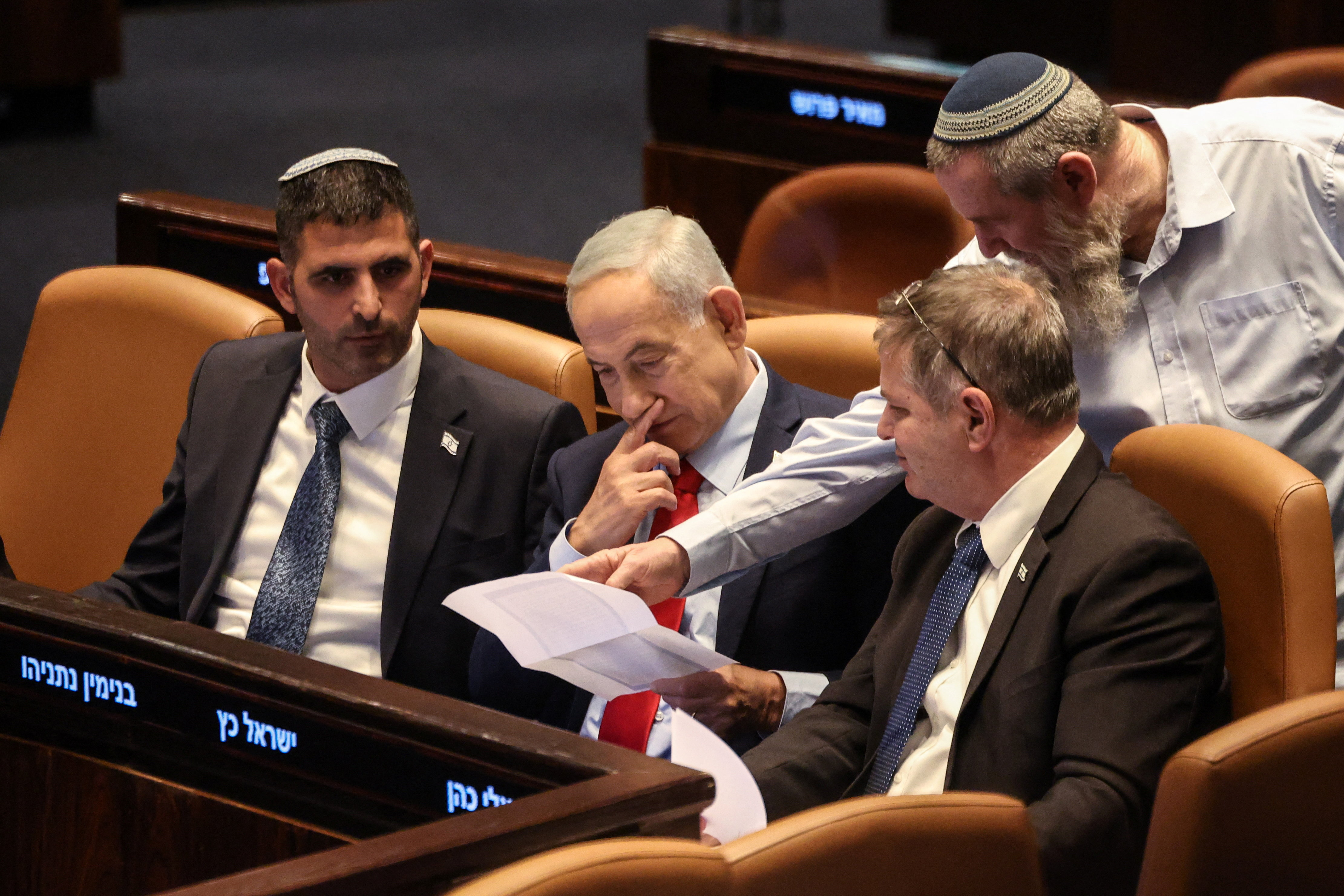 Israeli Prime Minister Benjamin Netanyahu holds a document at the plenum of the Knesset