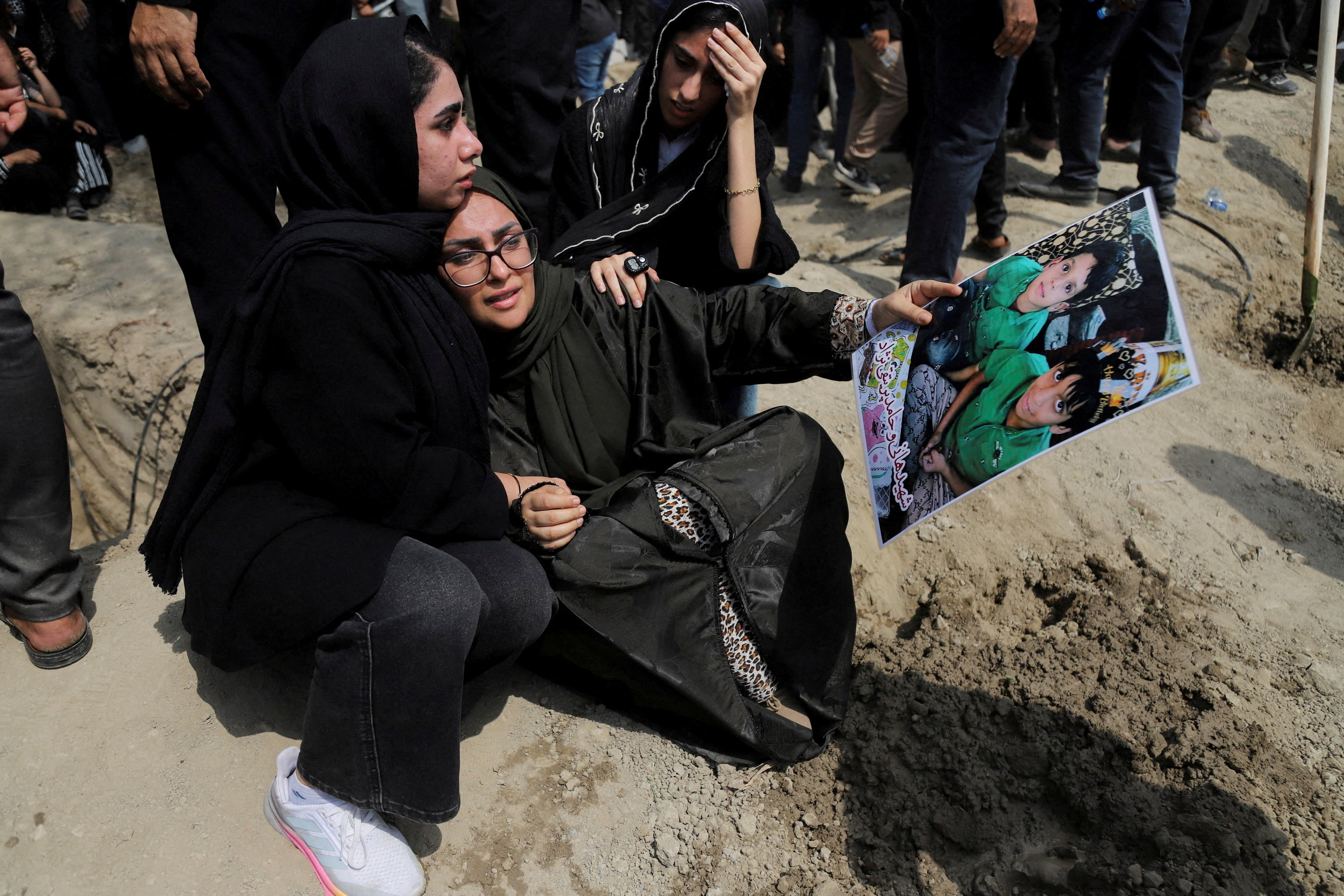 A woman holding a picture of children reacts during the funeral of the victims following a reported strike on a school, amid the U.S.-Israeli conflict with Iran, in Minab, Iran, March 3, 2026. Amirhossein Khorgooei/ISNA/WANA (West Asia News Agency) via REUTERS ATTENTION EDITORS - THIS PICTURE WAS PROVIDED BY A THIRD PARTY. TPX IMAGES OF THE DAY REFILE – REMOVING ATTRIBUTION TO STRIKE
