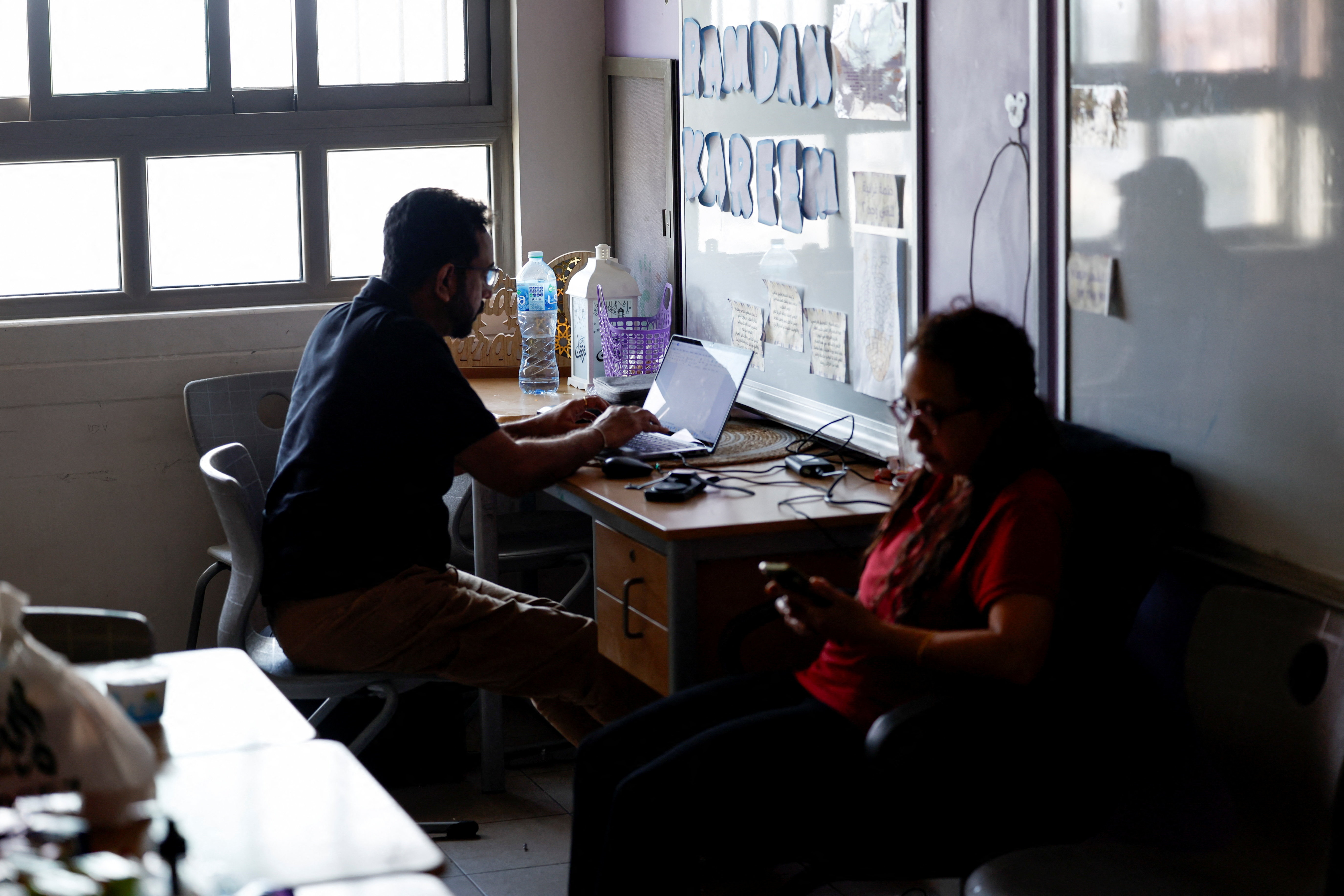 Indian nationals Ram Krishna, who works on his laptop, and his wife Vijian Lakshmi at a government provided shelter for people living near the US Navy Base during Iranian drone attacks, at Ghazi Al Gosaibi Secondary Girls School in Hamad Town, Bahrain, March 4, 2026