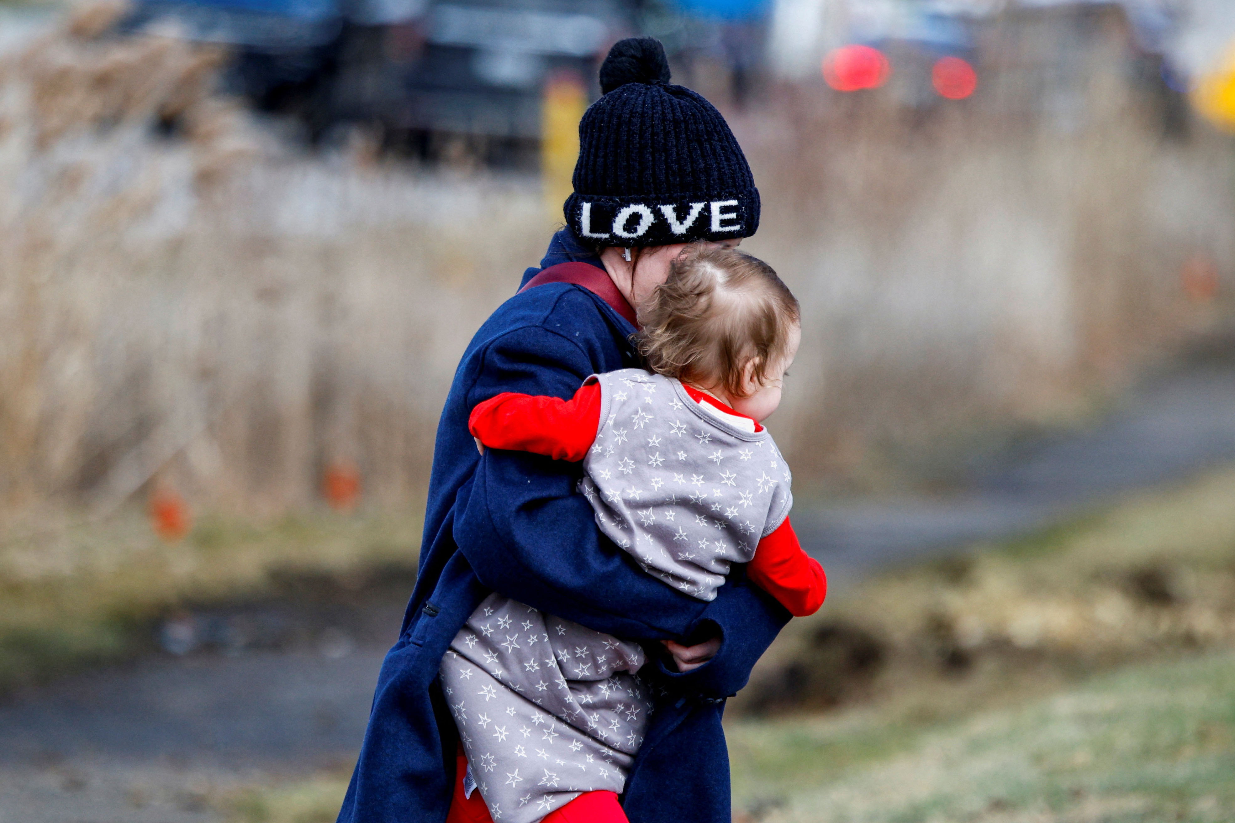 A mom carries her baby out of the Temple Israel Synagogue after the Michigan State Police reported an active shooting incident there, in West Bloomfield, Michigan, U.S., March 12, 2026. [Rebecca Cook/Reuters]