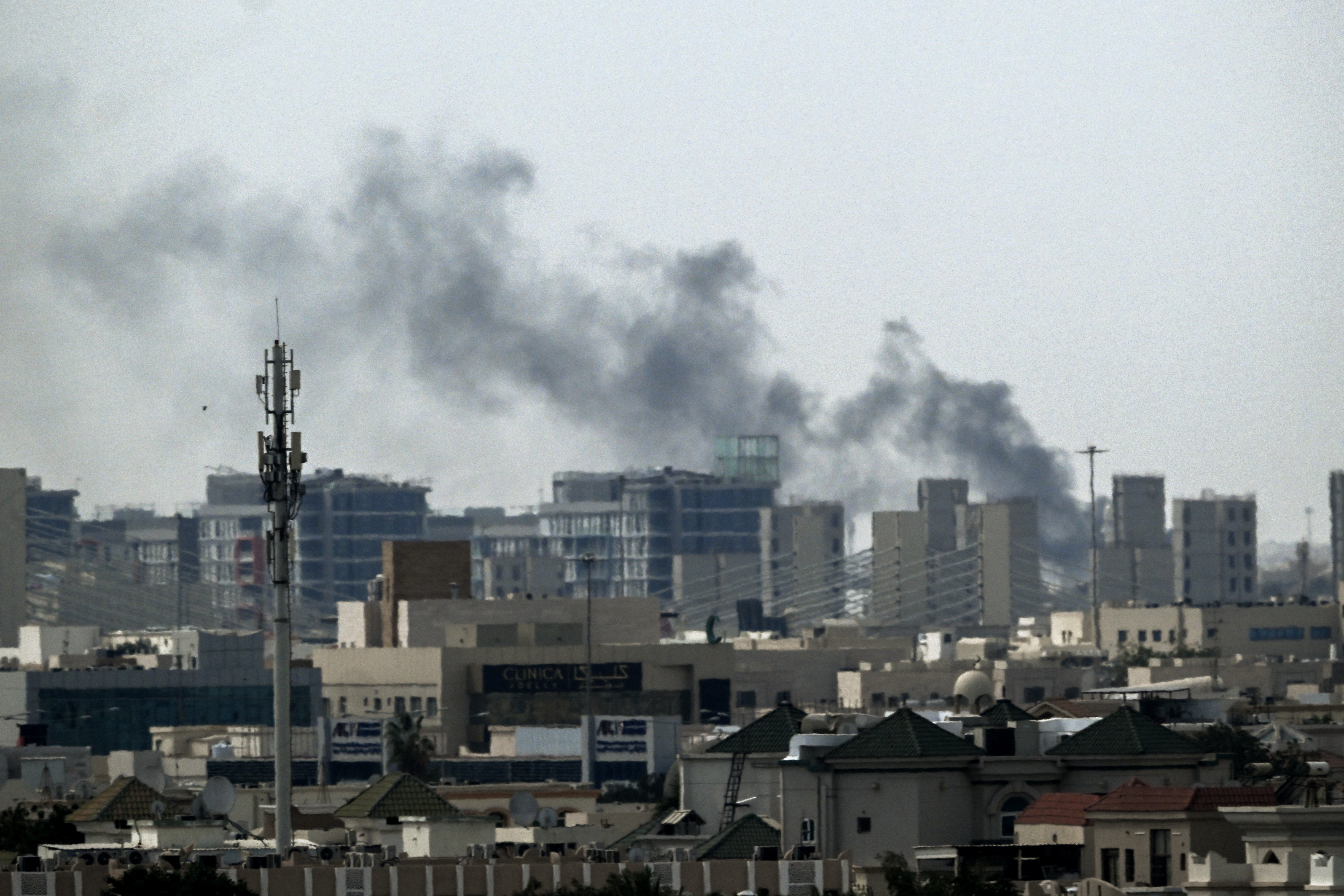 A plume of smoke rises over buildings.