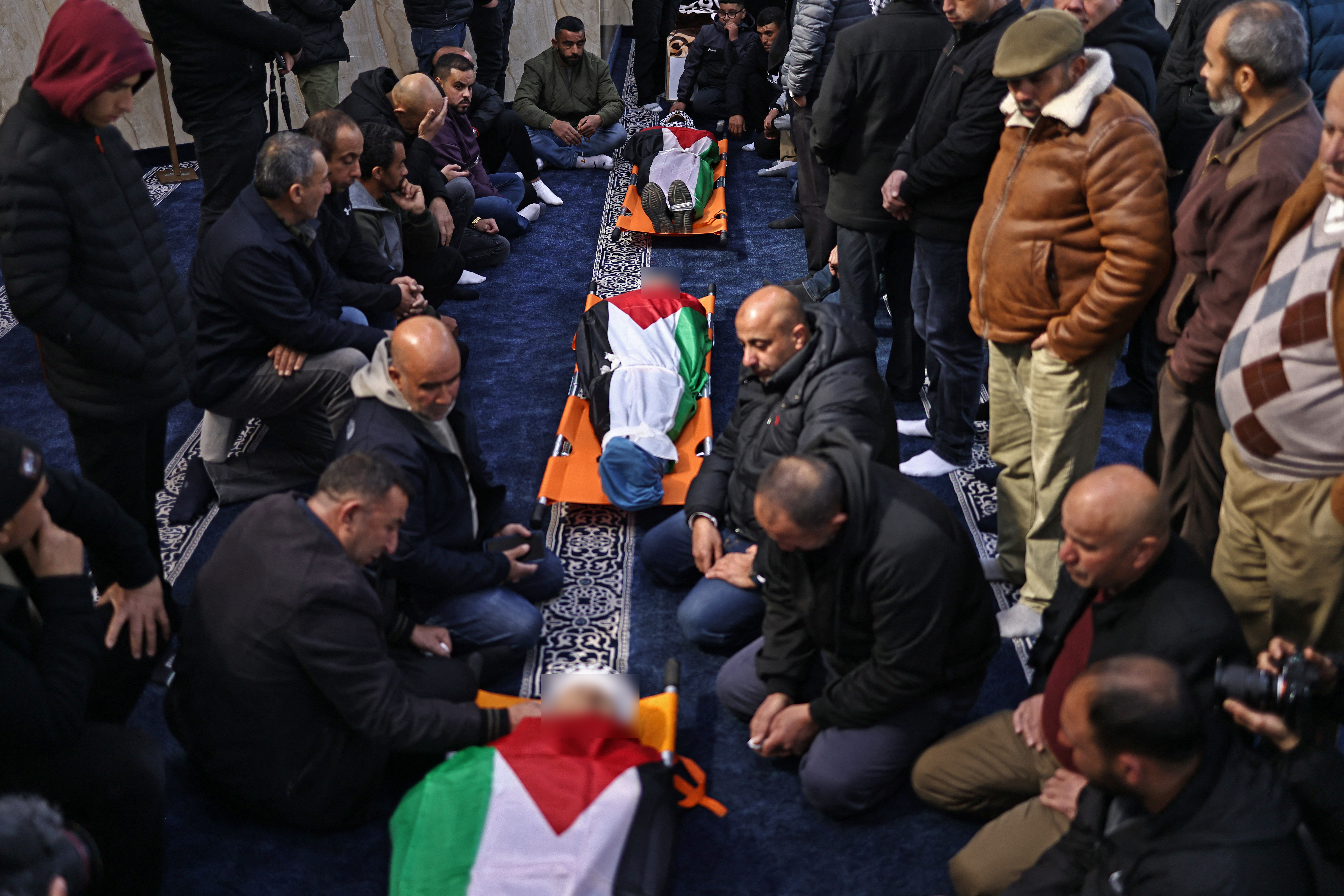 EDITORS NOTE: Graphic content / People mourn next to the bodies of three Palestinians killed in an Israeli settler attack, in Abu Falah town, northeast of Ramallah on March 8, 2026. Palestinian authorities and the Israeli military said on March 8 that three Palestinians were killed during an Israeli settler attack in the occupied West Bank, the second deadly incident reported in as many days. (Photo by Zain JAAFAR / AFP)