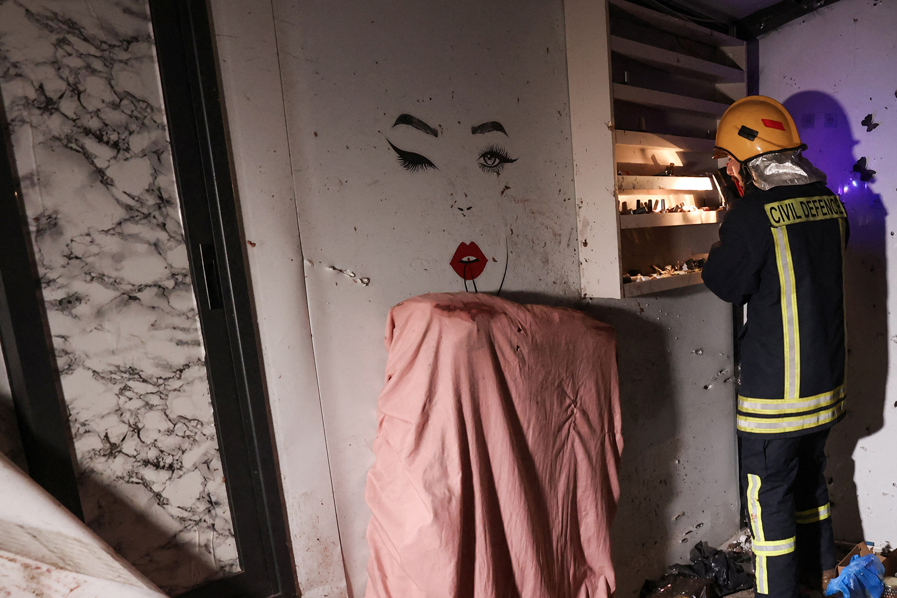 A Palestinian civil defence worker inspects the site where shrapnel from projectiles fell in Beit Awa near the Israeli-occupied West Bank city of Hebron on March 18, 2026. [Hazem Bader/AFP]