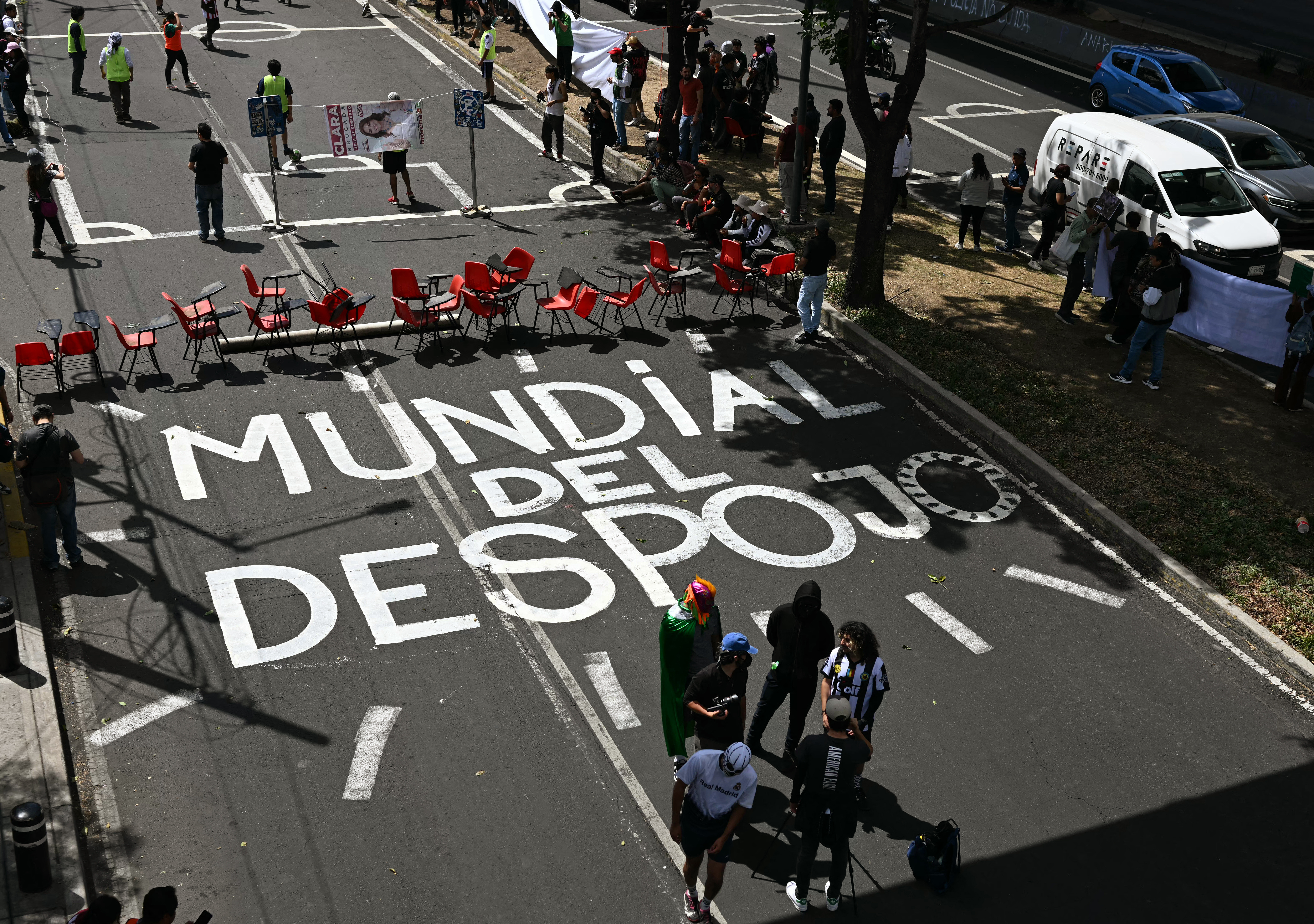People stand next to a sign in the floor that reads 'World Cup of eviction' during a demonstration against FIFA before the inauguration of Banorte Stadium (formerly known as Azteca), with a friendly match between Mexico and Portugal, in Mexico City on March 28, 2026. (Photo by YURI CORTEZ / AFP)