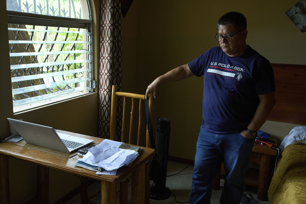 A Salvadoran journalist stands next to his laptop