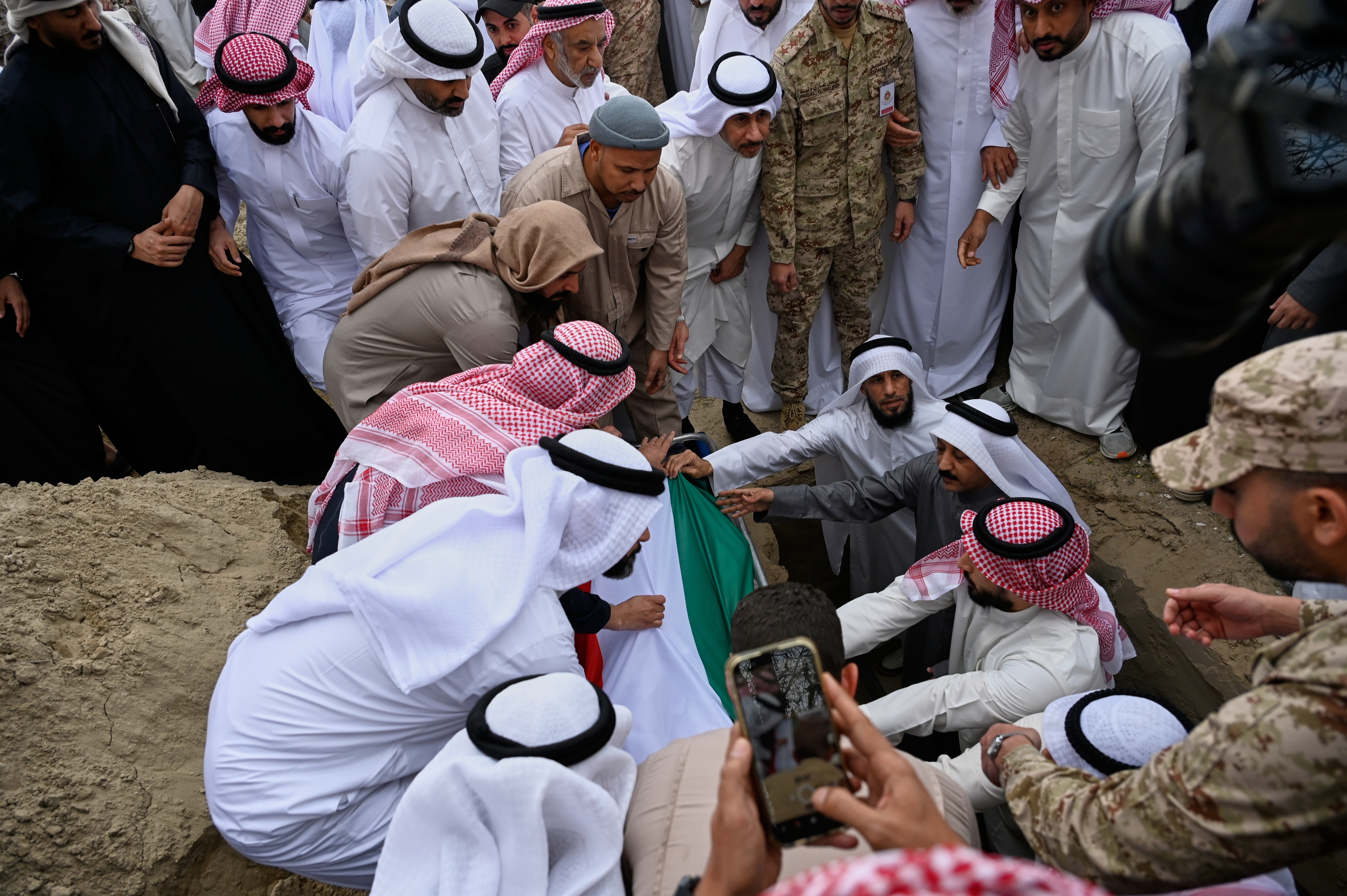 The body of one of two Kuwaiti navy soldiers killed on duty during Iranian missile and drone attacks on Kuwait is lowered into the grave during their funeral at the Sulaibikhat cemetery in Kuwait City, Kuwait, Tuesday, March 3, 2026.(AP Photo/Jaber Abdulkhaleg)