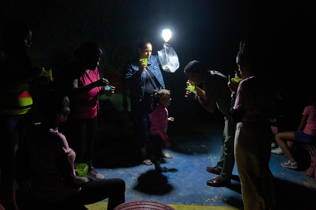 people use a light as they eat cups of soup during a blackout in Cuba