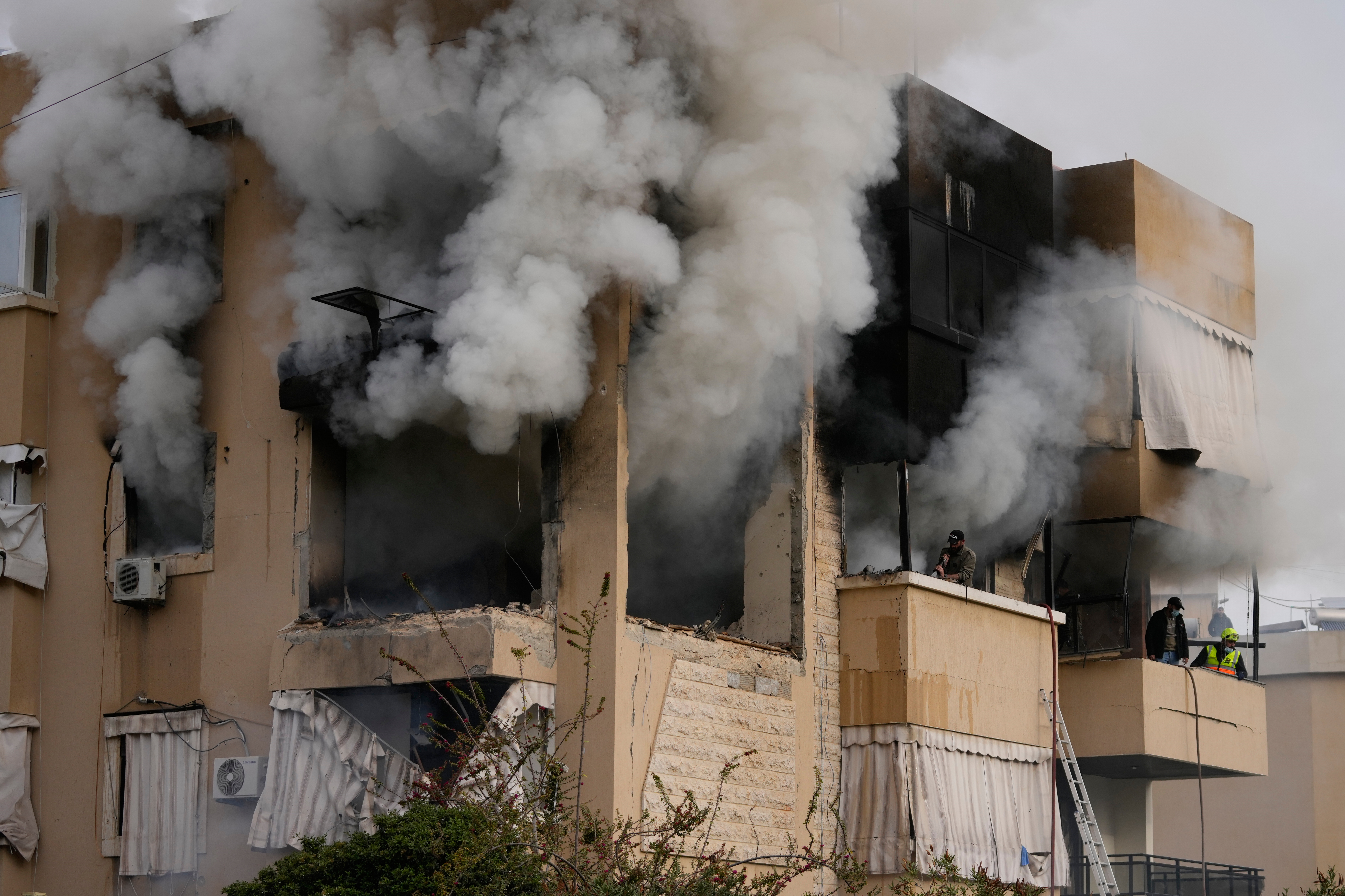 Rescue workers inspect an apartment damaged in an Israeli air raid as thick smoke fills the building in the southern port city of Sidon