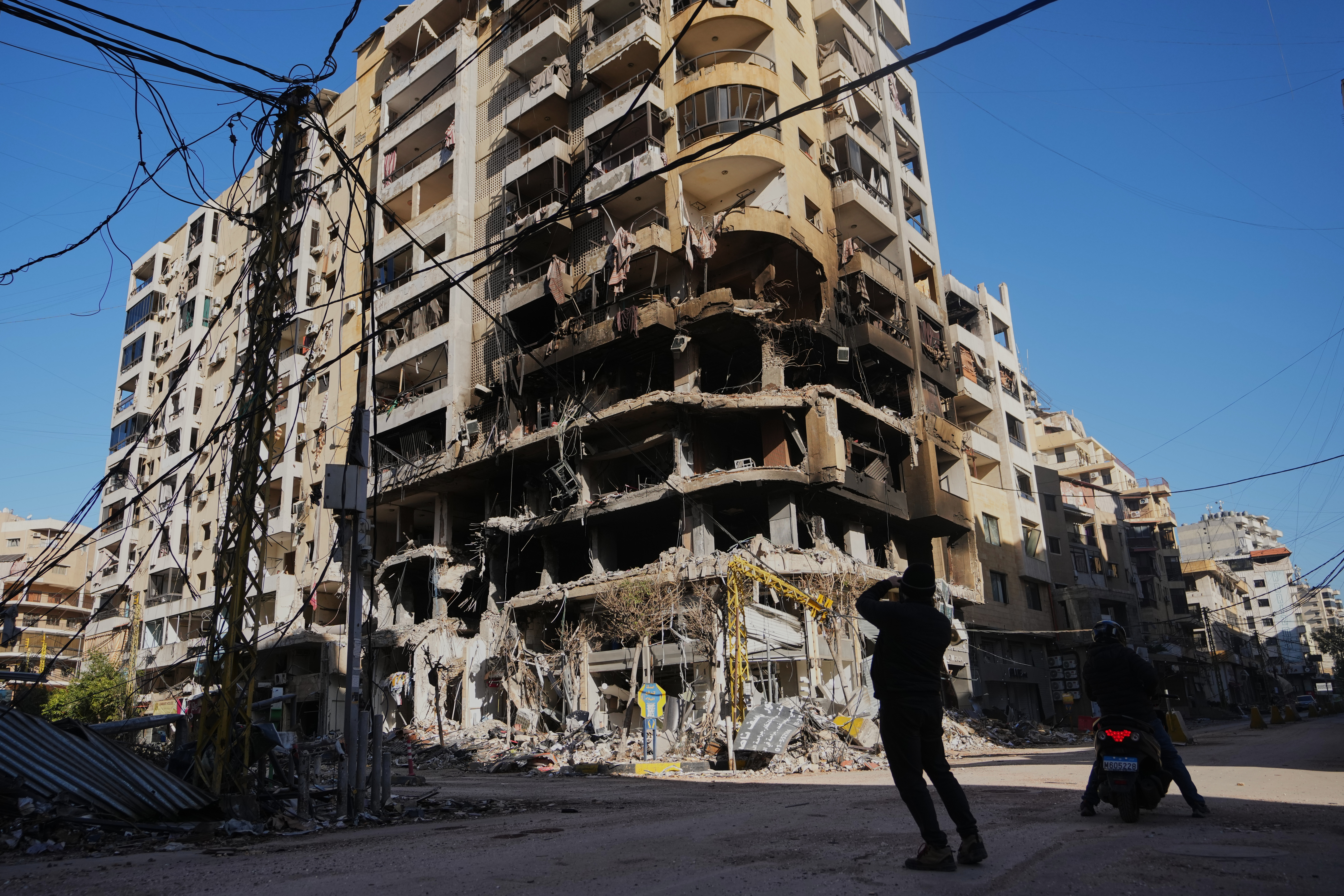 A man photographs a building damaged by an air strike.