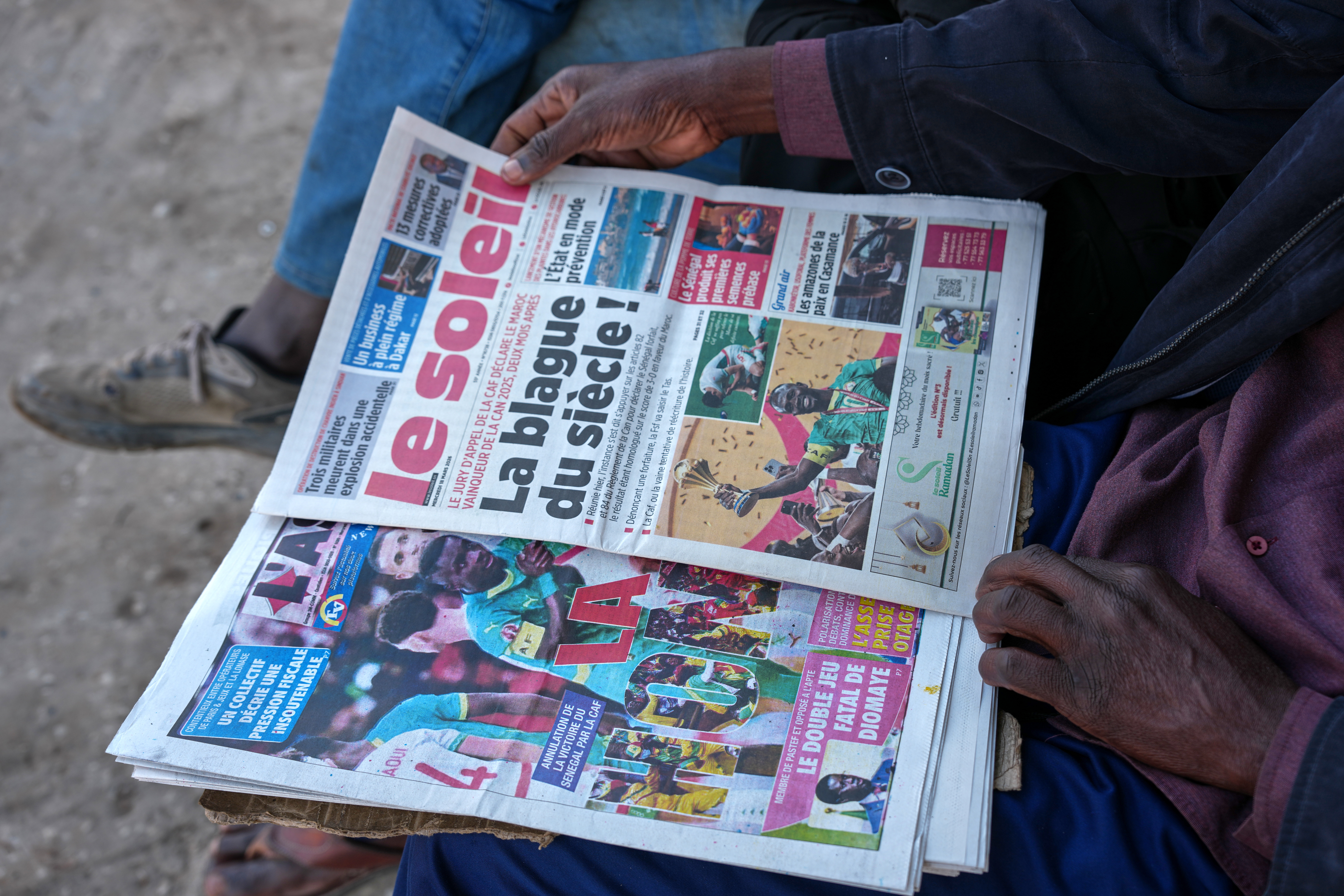 People read newspapers reporting on the Confederation of African Football decision stripping the Senegal national football team of their Africa Cup of Nations title and awarding it to Morocco national football team in Dakar, Senegal