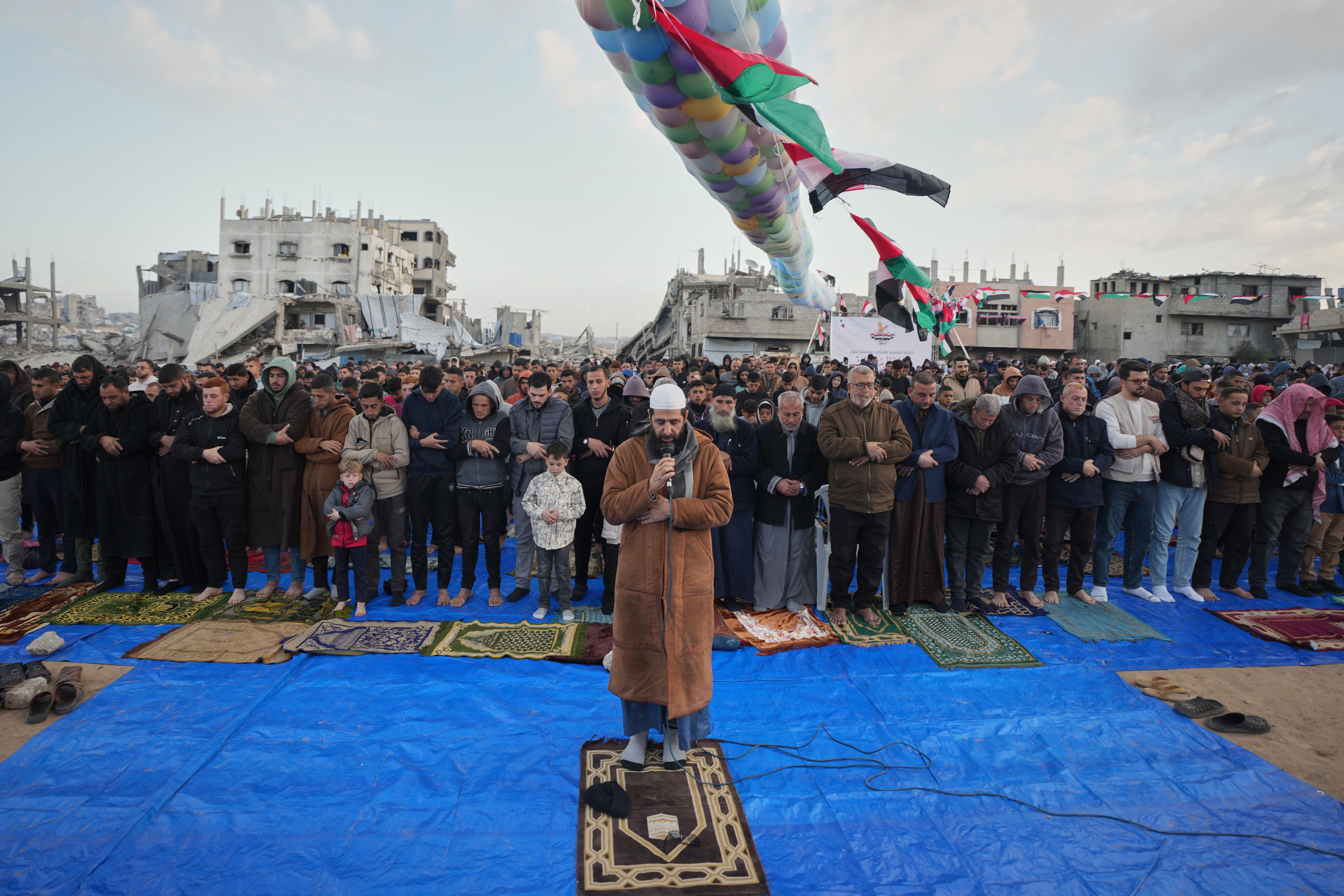 People offer communal prayers amid the rubble of destroyed buildings.