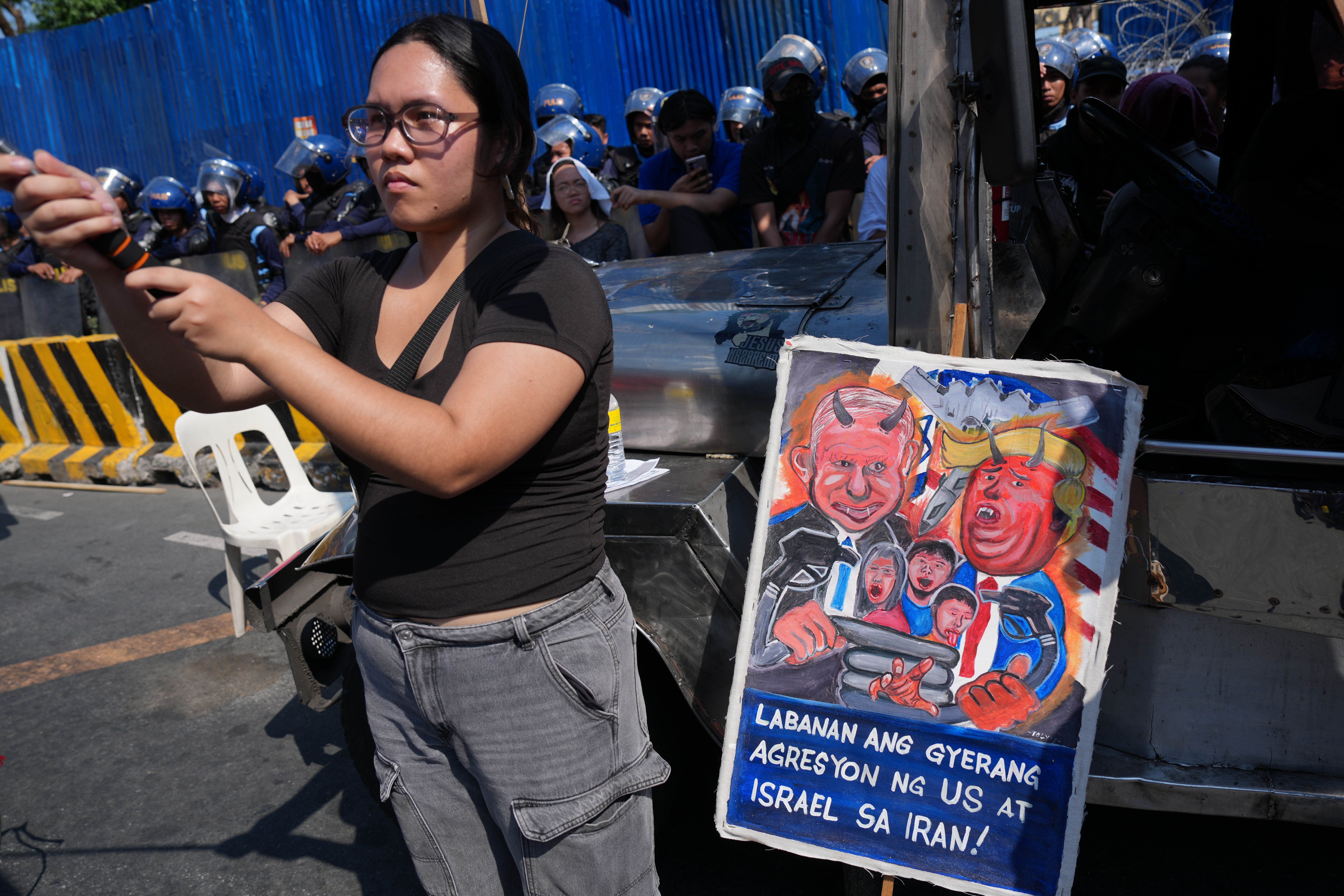 A protester stands beside a caricature of Israeli Prime Minister Benjamin Netanyahu and US President Donald Trump during a rally.