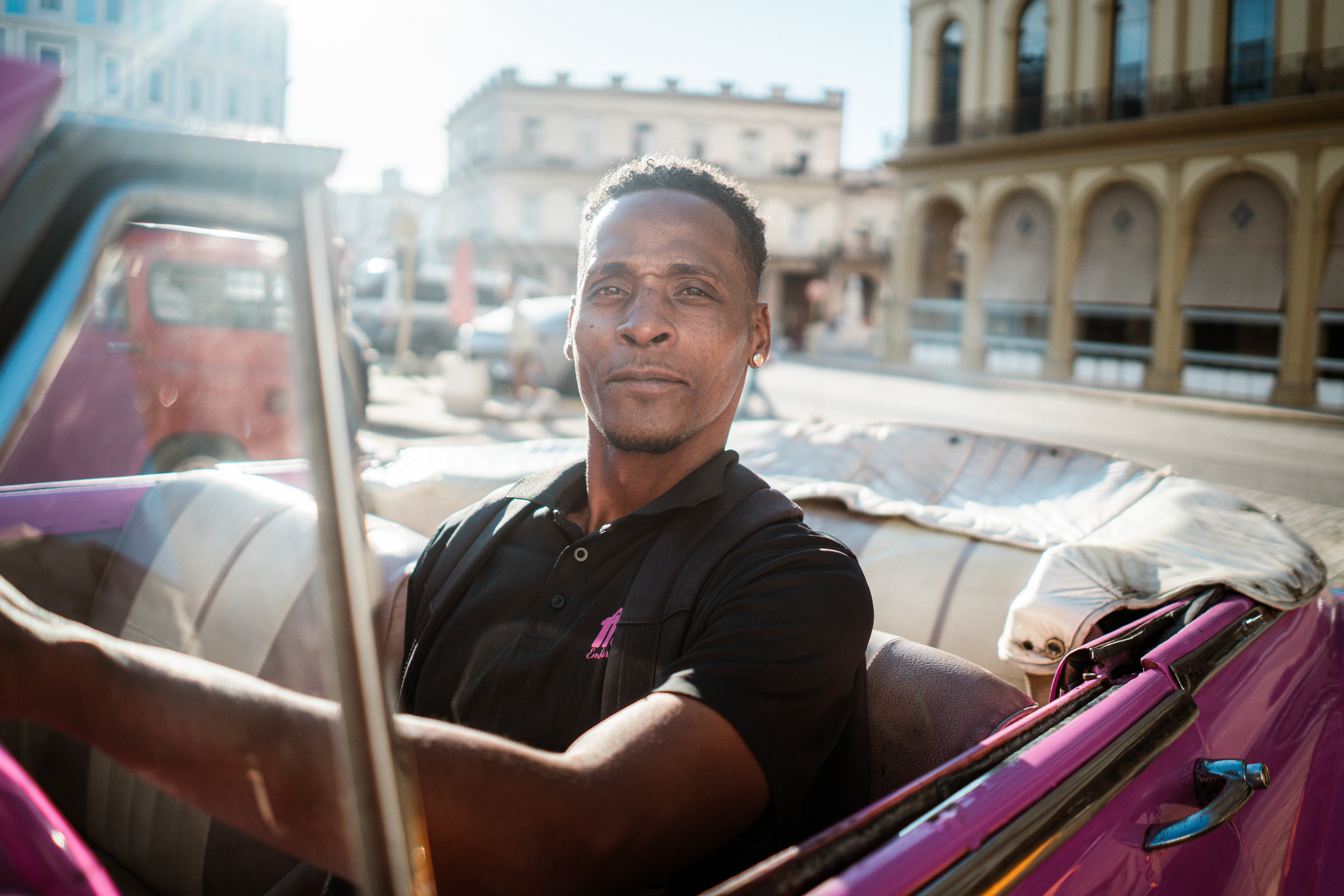 A man sits in a pink Chevrolet waiting for taxi customers