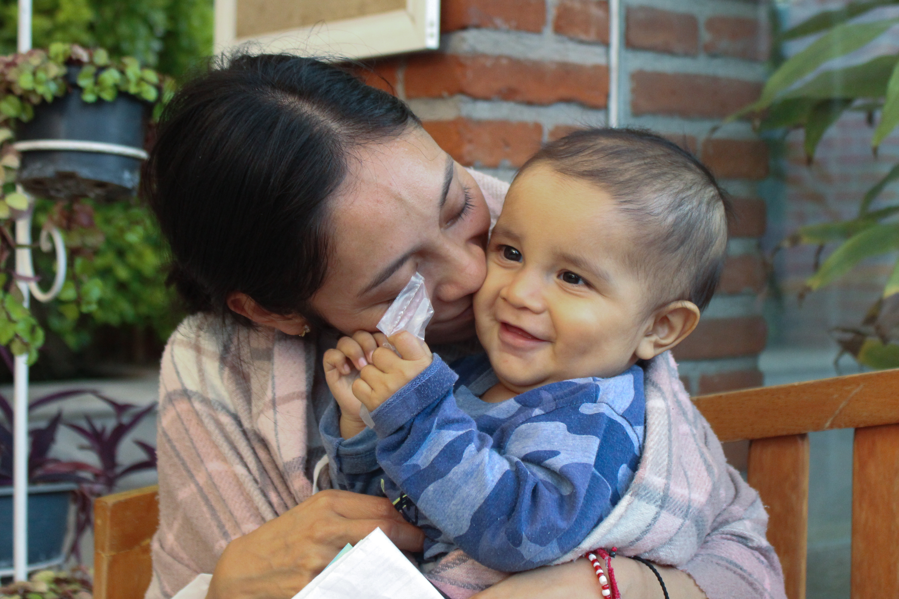 Luisa leans in to kiss Juan de Jesús on the cheek while he grips medication given to him by the doctor that morning, following a night of fever and restlessness_-1773831279