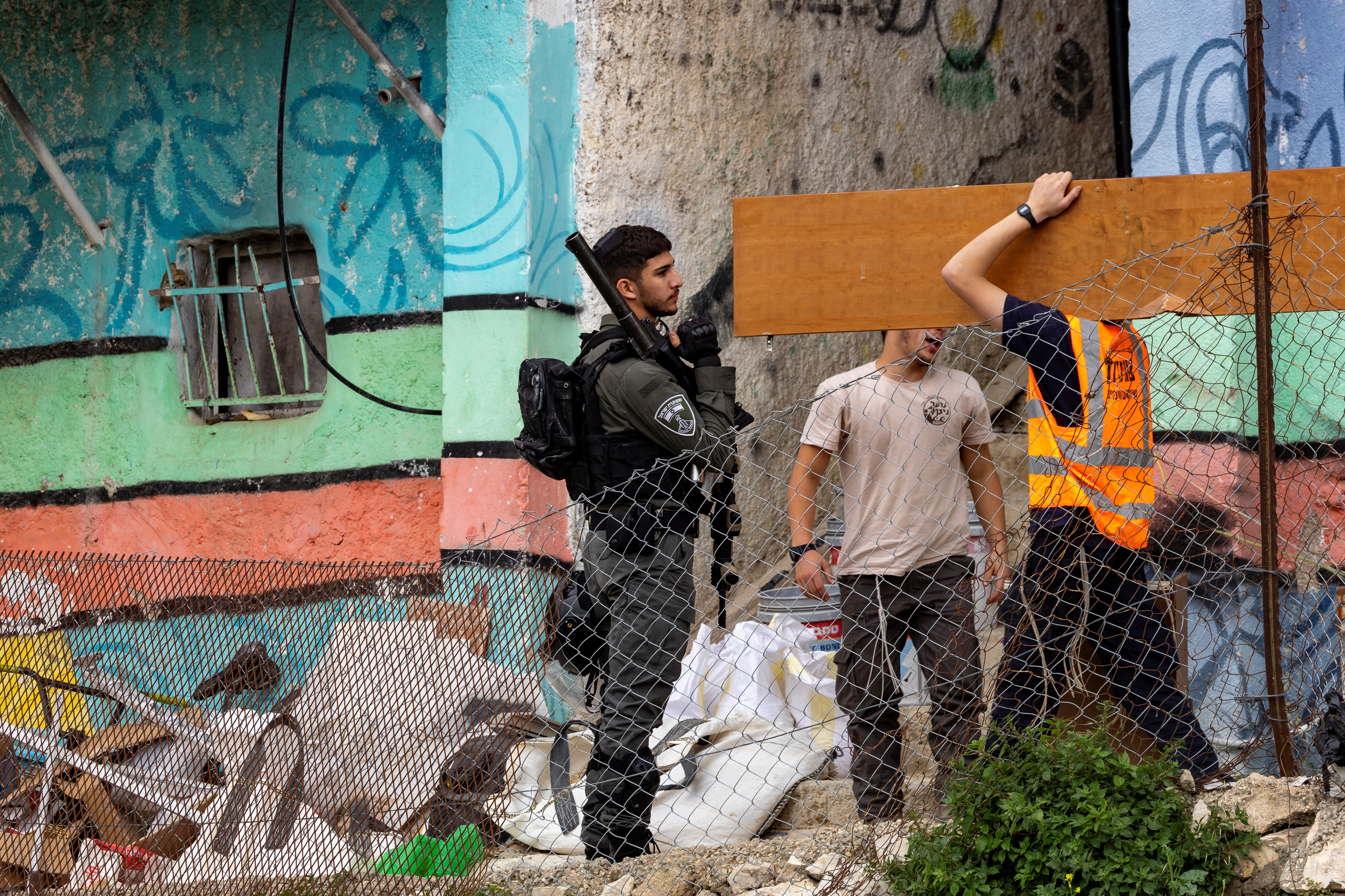 An israeli soldier look on as Israeli authority employees empty a Palestinian home as 11 Palestinian families in the Batan al-Hawa area of Silwan are evicted to make room for Israeli settlers, in the predominantly Arab neighbourhood of Silwan, in East Jerusalem on March 25, 2026.