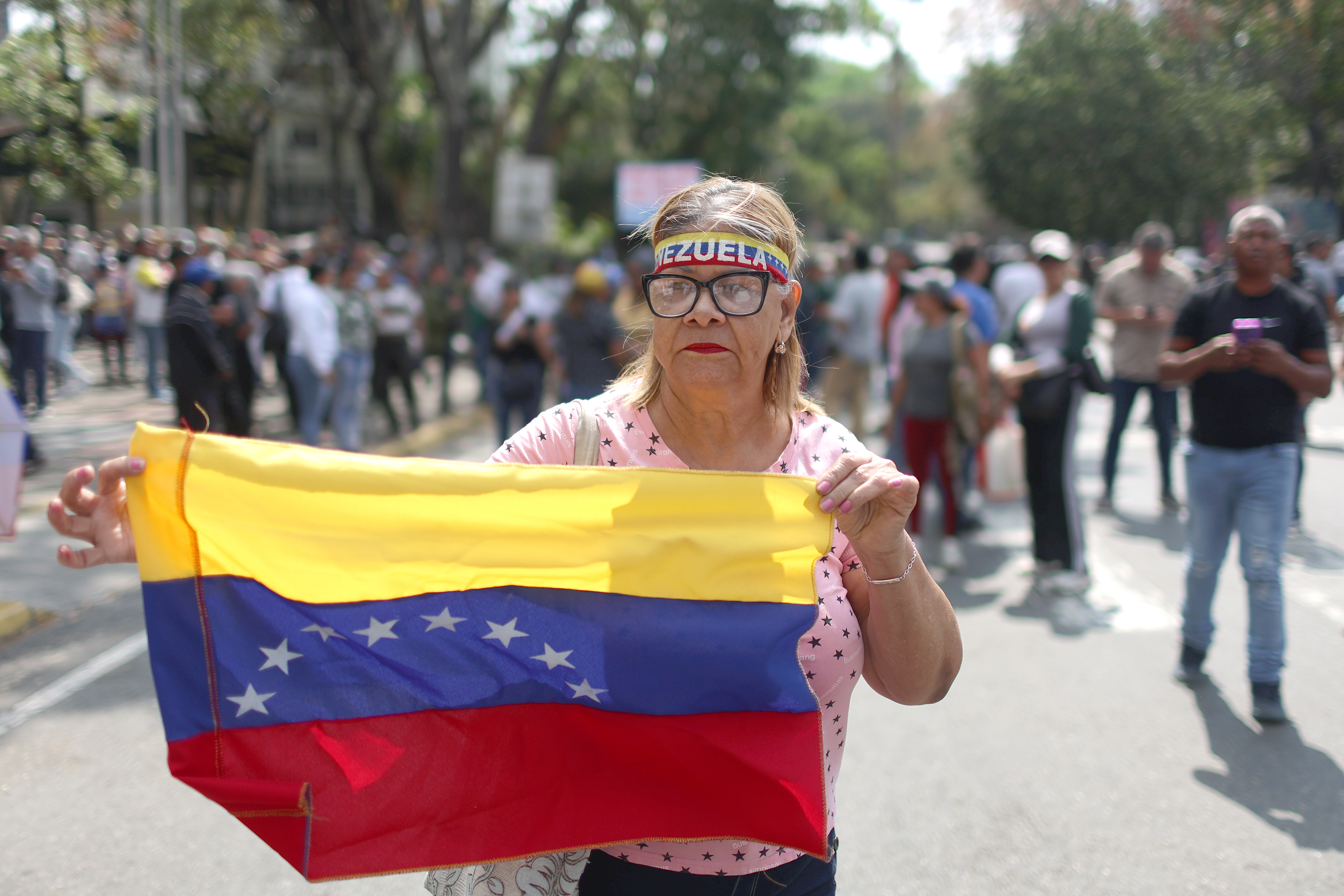 epa12814657 A person holds the Venezuelan flag during a protest over wages and pensions in Caracas, Venezuela, 12 March 2026. EPA/MIGUEL GUTIERREZ