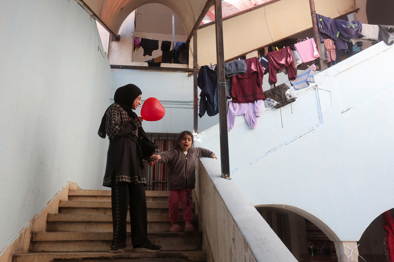 A child reacts next to a woman as displaced people take shelter inside a school in Sidon, Lebanon on March 11, 2026, following an escalation between Hezbollah and Israel amid the US-Israeli conflict with Iran. [Aziz Taher/Reuters]