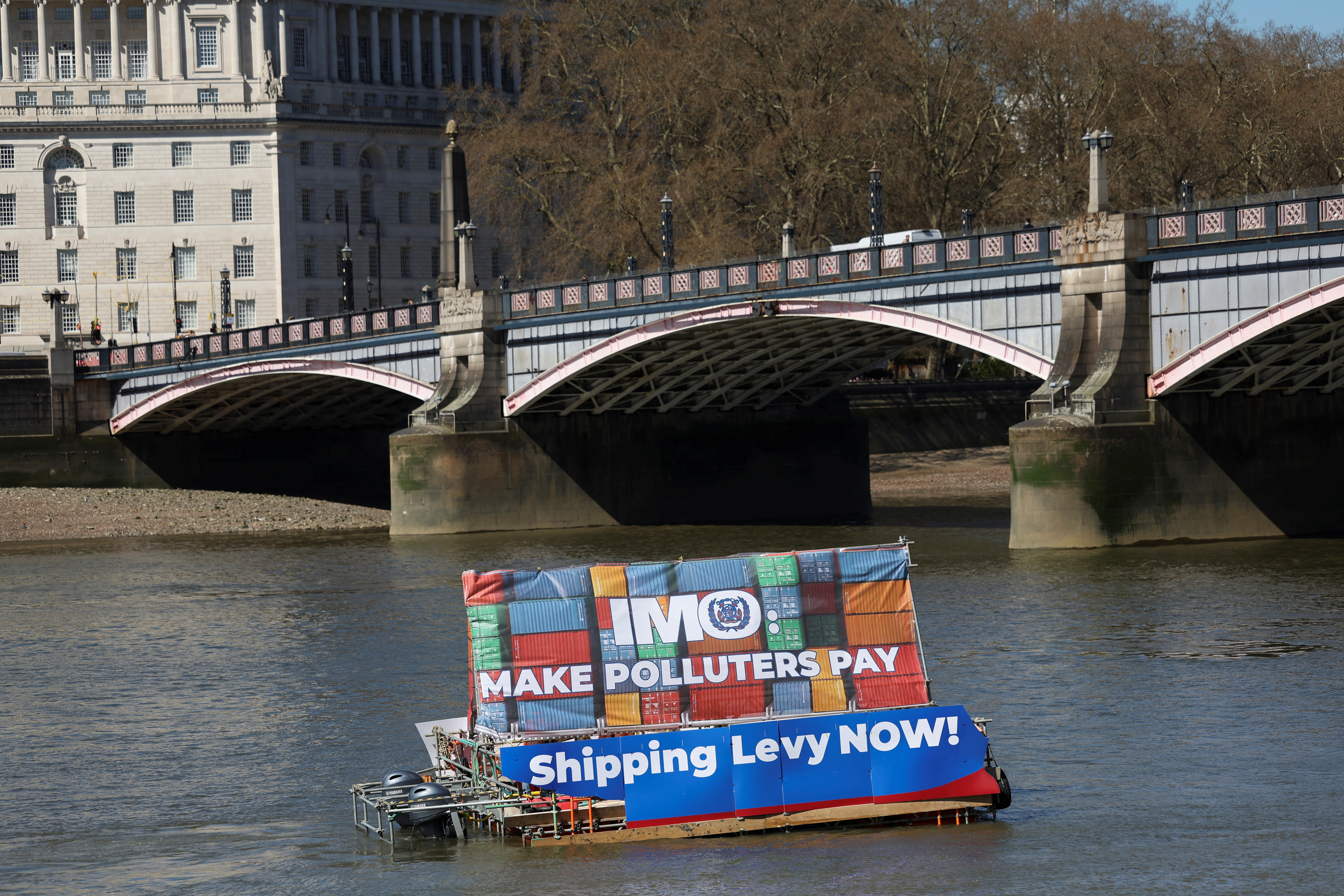 Climate activists display a banner on the River Thames, calling for polluters to pay as the International Maritime Organization begins its carbon price working group meeting in London, Britain, April 1, 2025. REUTERS/Sodiq Adelakun