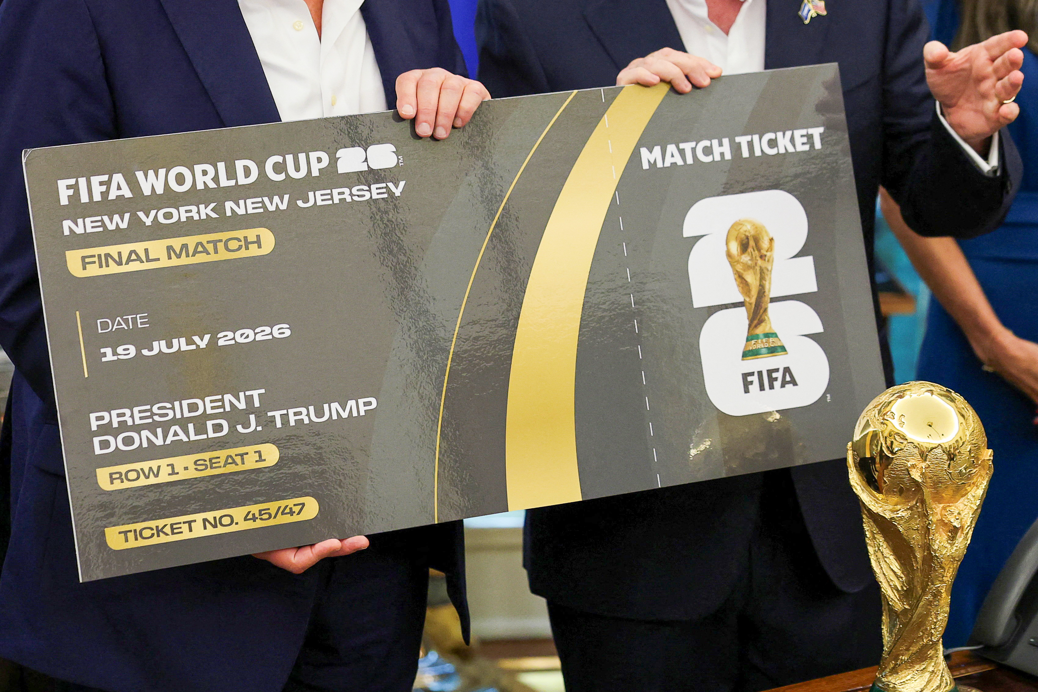 U.S. President Donald Trump and FIFA president Gianni Infantino hold a 2026 FIFA World Cup final match ticket that was presented to President Trump, as the President makes an announcement on the 2026 FIFA World Cup, while U.S. Homeland Security Secretary Kristi Noem stands, in the Oval Office at the White House in Washington, D.C., U.S., August 22, 2025. REUTERS/Jonathan Ernst