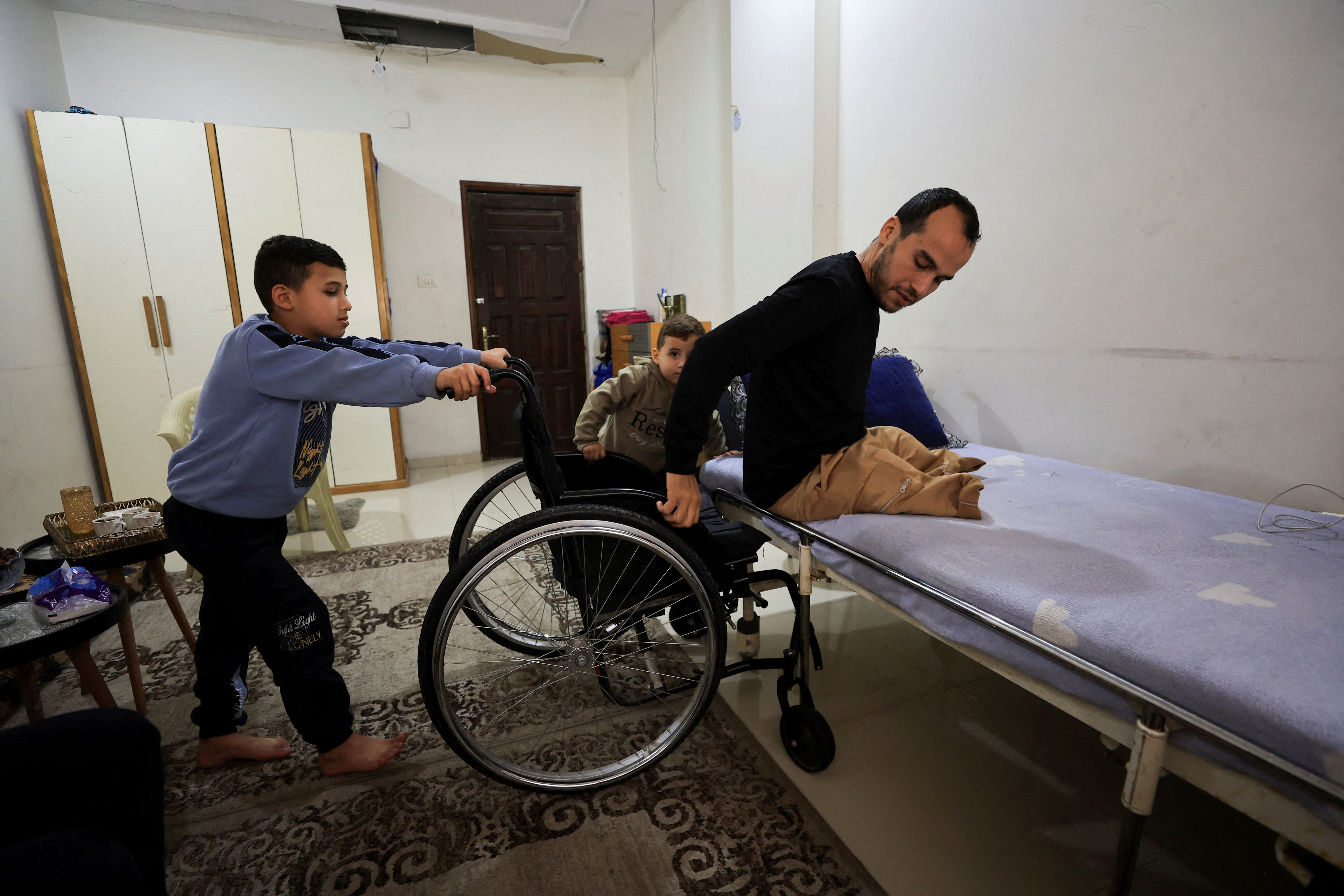 Palestinian amputee Omar Abu Ali, 34, who was injured in an Israeli strike, transfers from his wheelchair onto a bed at his home, in Gaza City, April 1, 2026. REUTERS/Dawoud Abu Alkas TPX IMAGES OF THE DAY