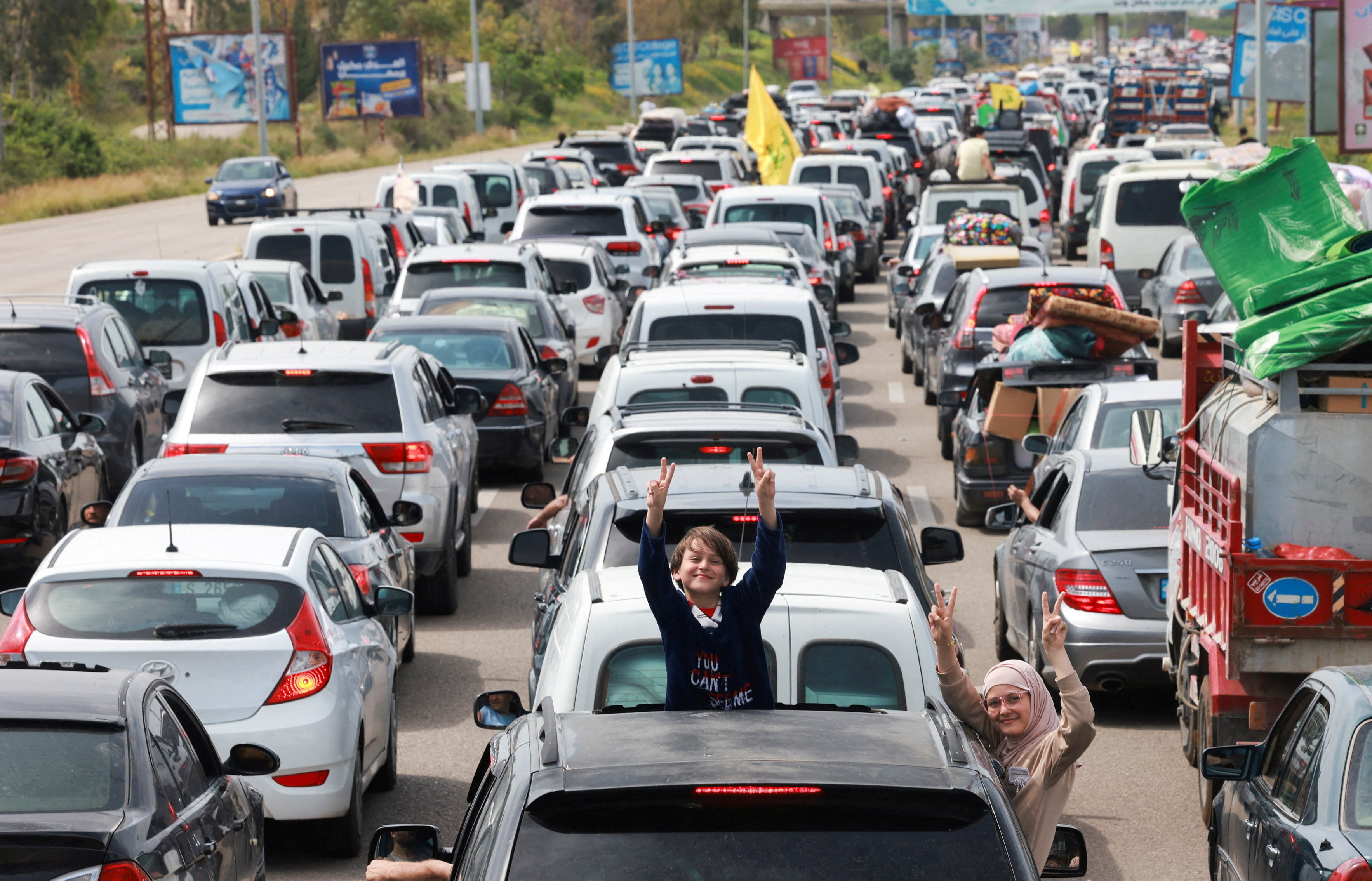 Children gesture from a vehicle as displaced people make their way to return to their homes after a 10-day ceasefire between Lebanon and Israel went into effect,
