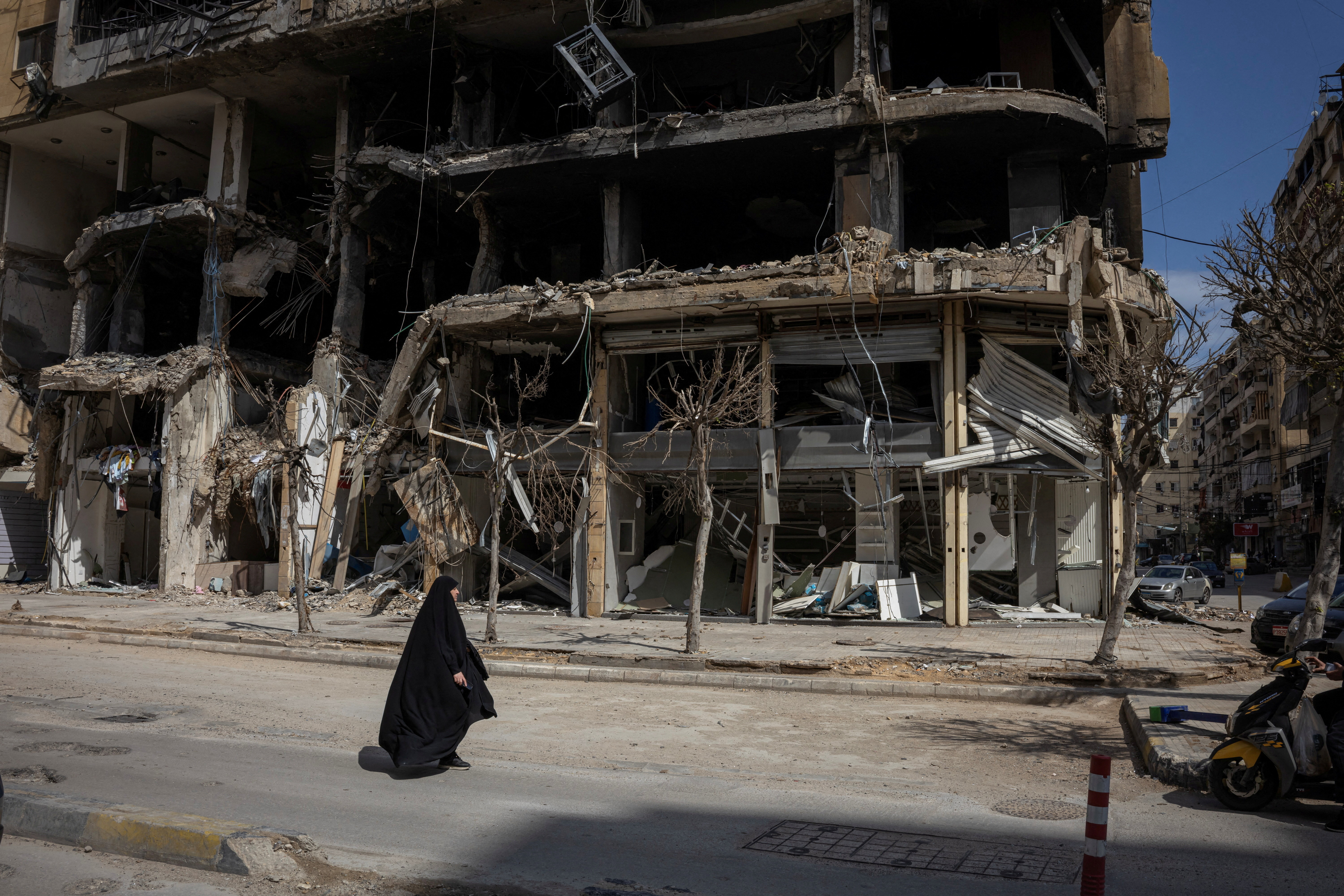 A woman walks past a destroyed building in Beirut